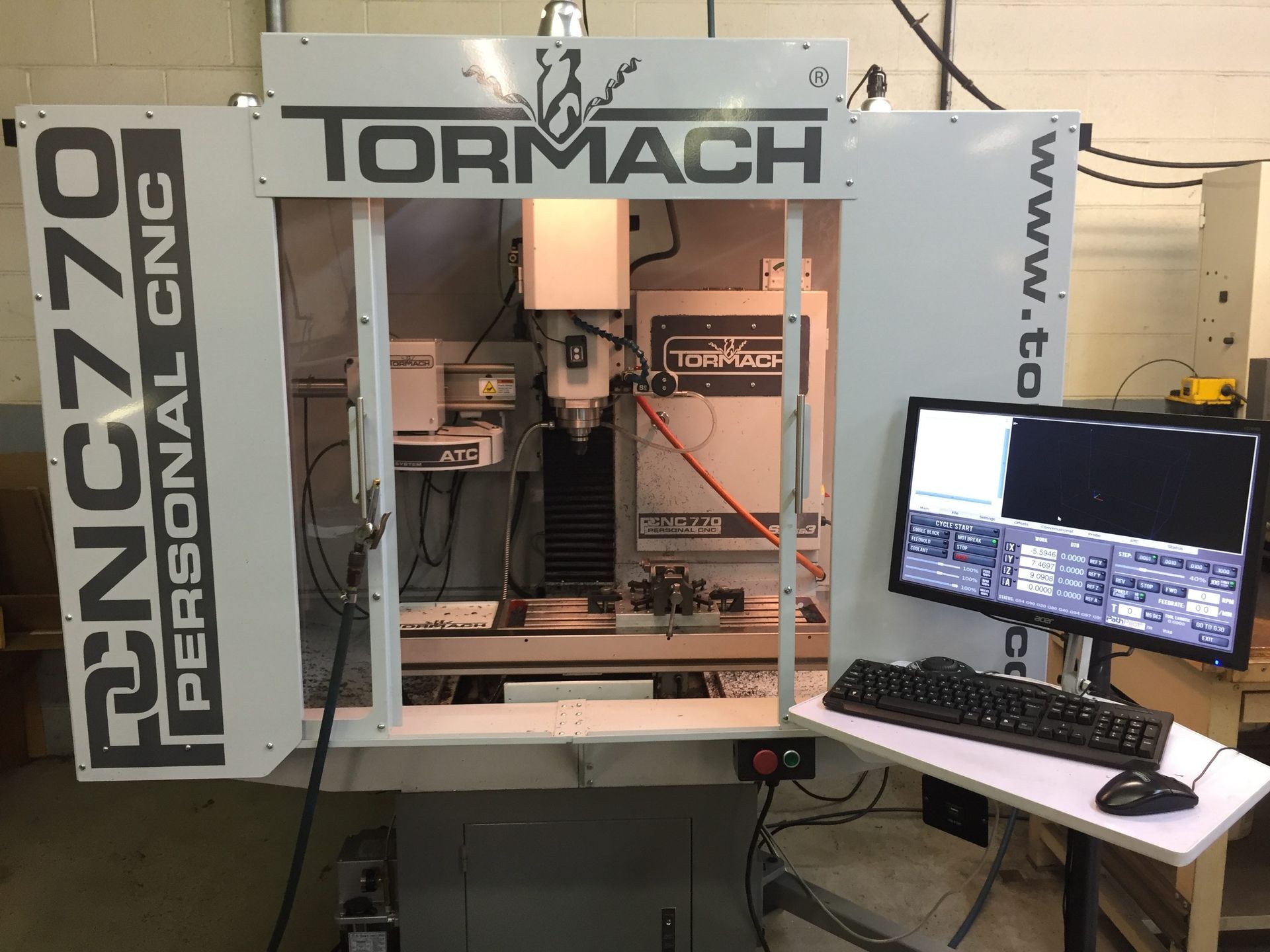 Tormach PCNC 770 CNC milling machine with open doors, computer monitor and keyboard to the right.