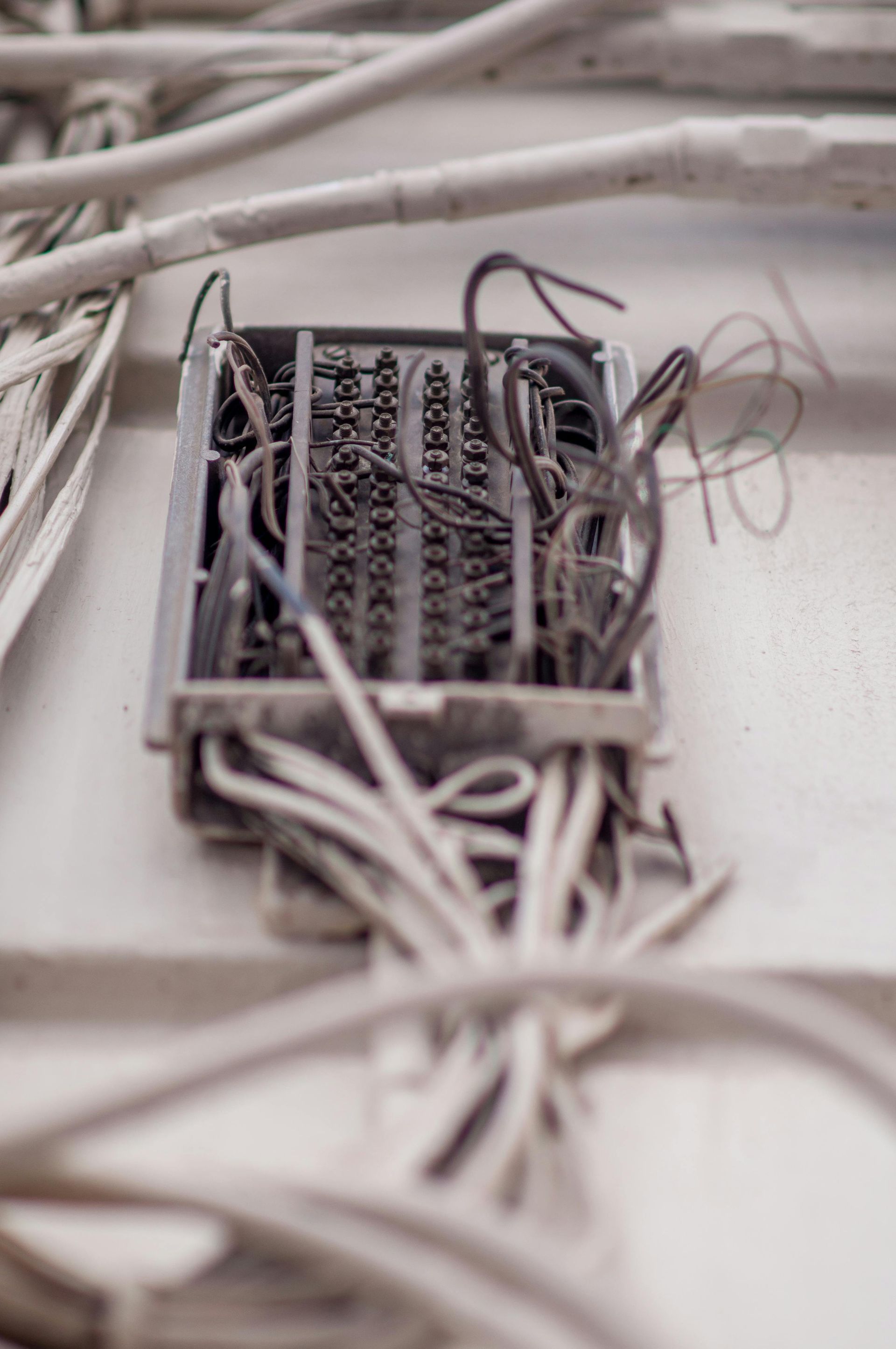 A jumbled electrical junction box with wires emerging from a white wall.