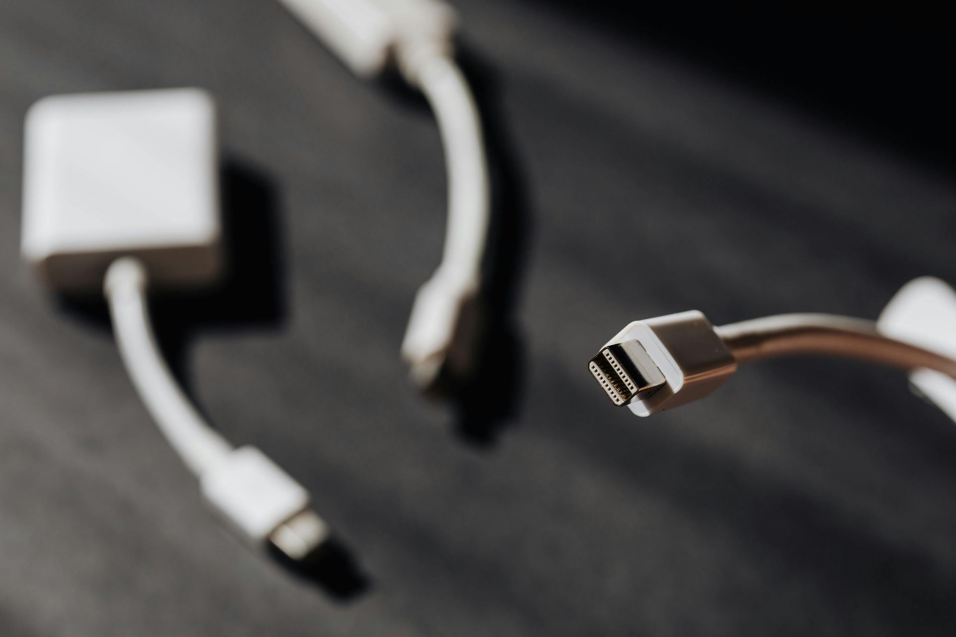 White cables and adaptors on a dark surface, focus on a close-up of an HDMI connector.