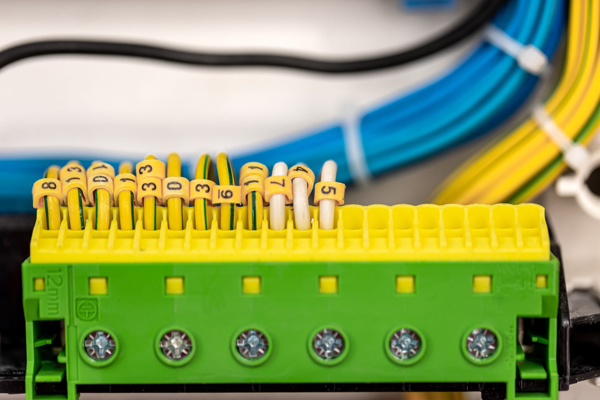 Close-up of numbered electrical terminal block with wires, green and yellow.