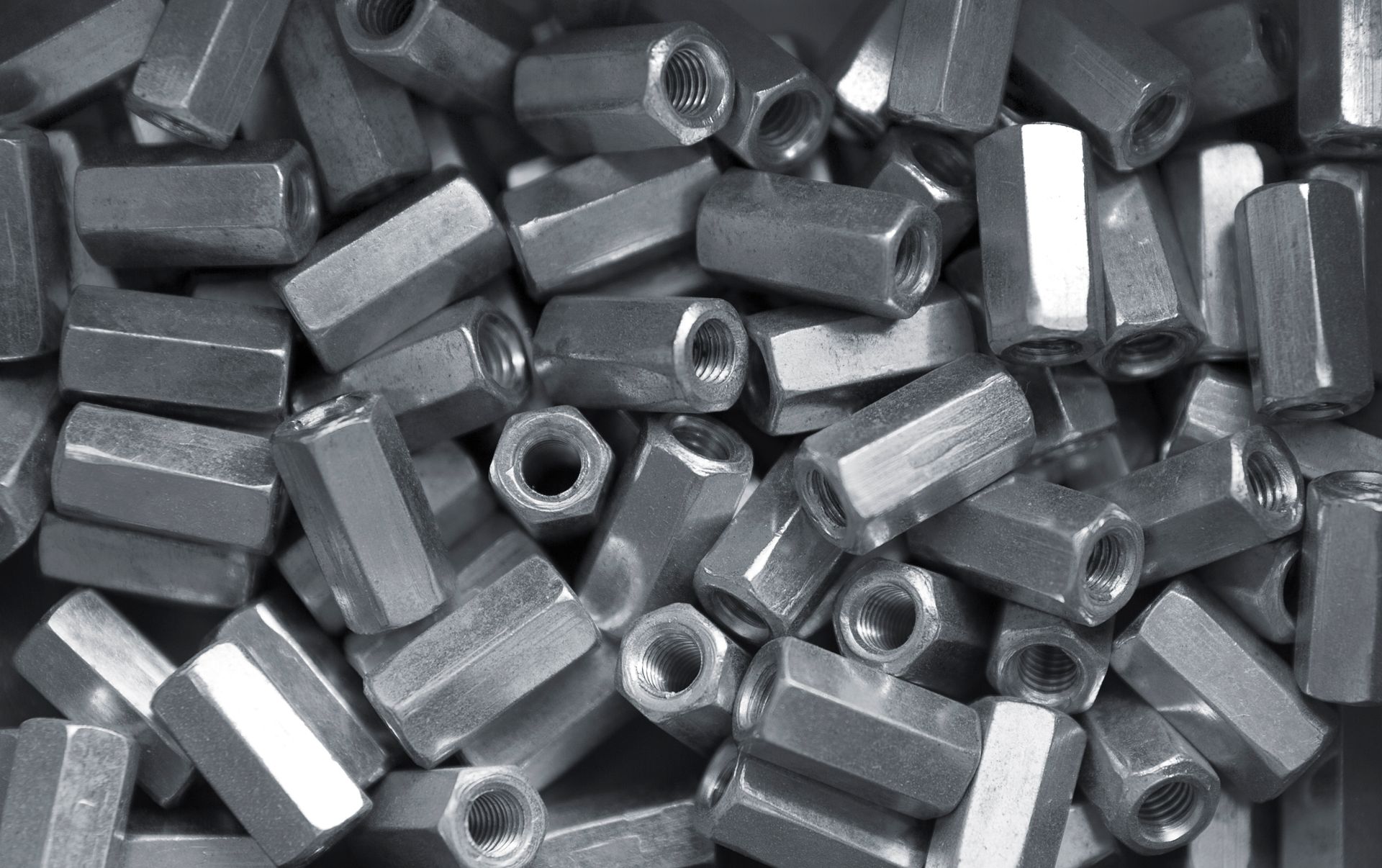 A pile of nuts and bolts in a metal box.