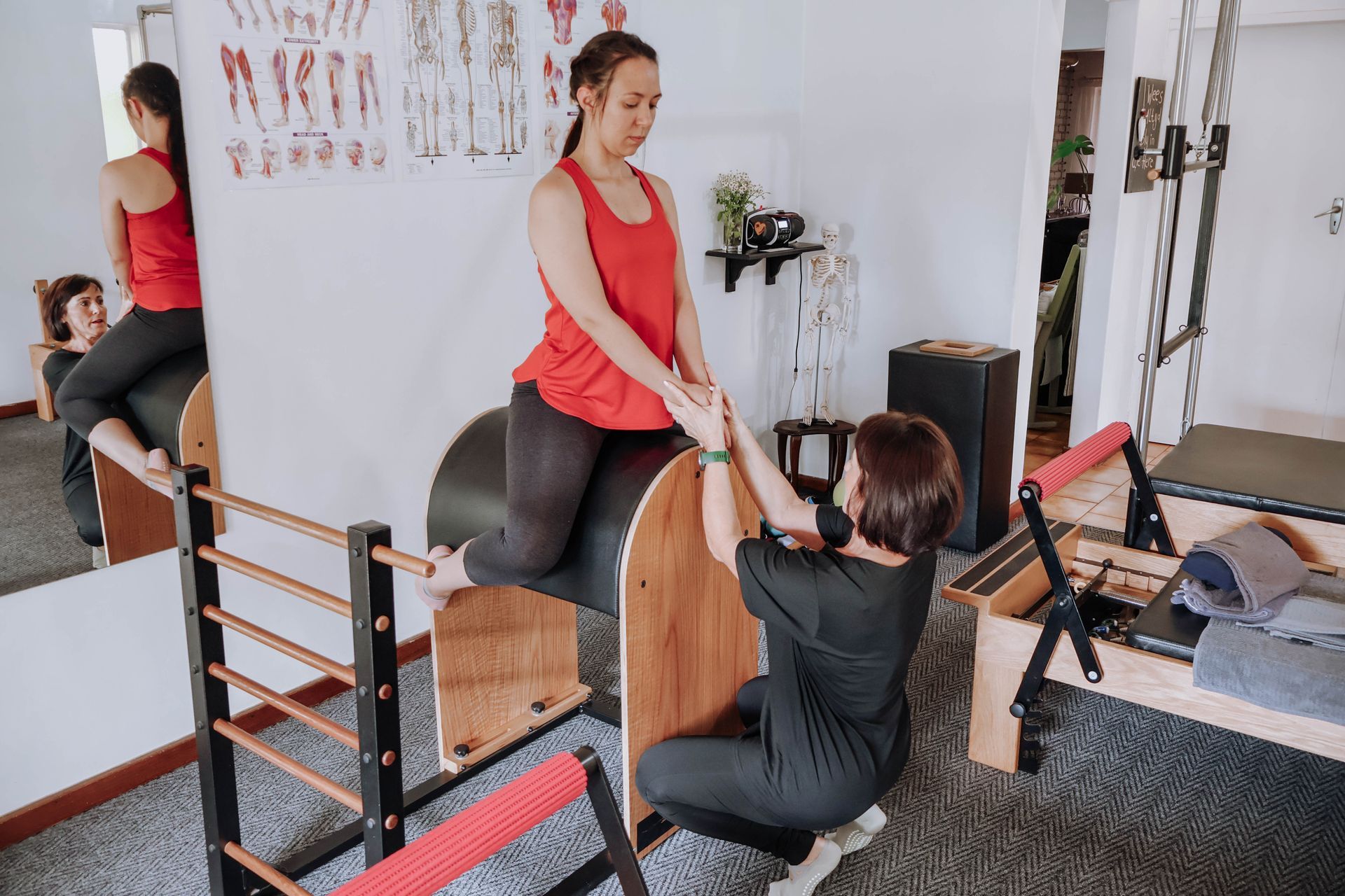 Pilates instructor assisting a client using a reformer in a studio