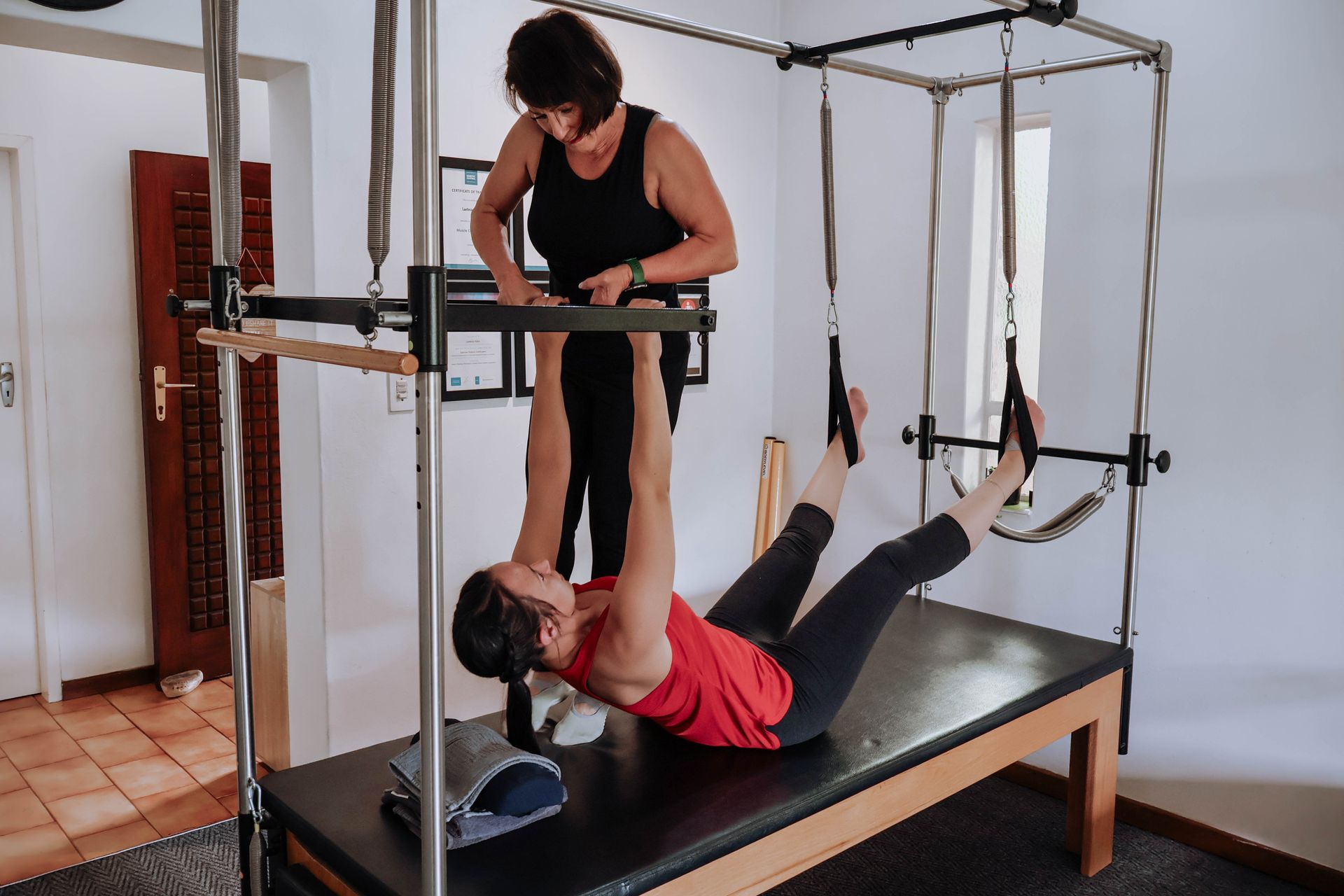 Two people doing Pilates on a reformer machine in a studio