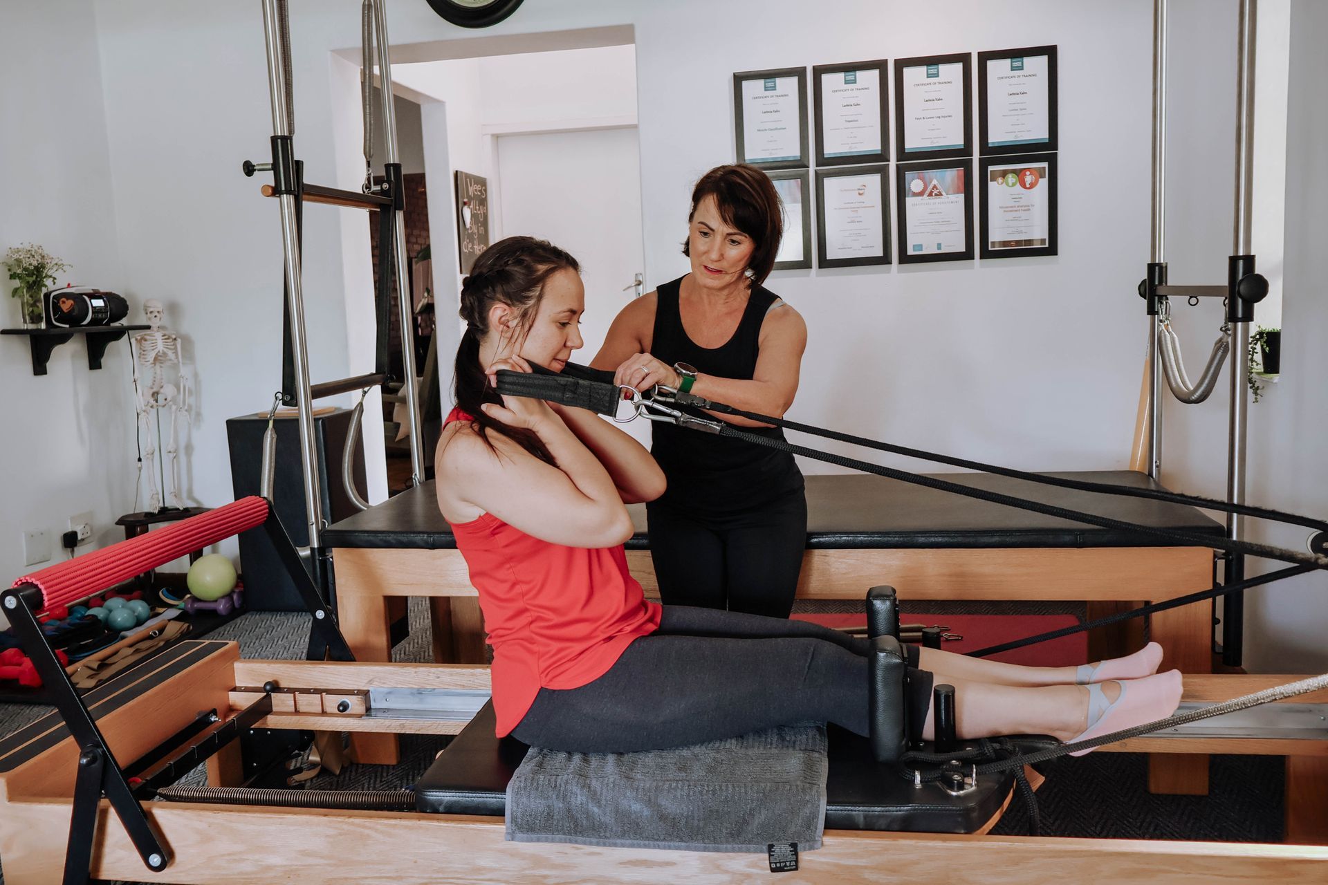 Pilates instructor guiding a woman on reformer equipment in a studio