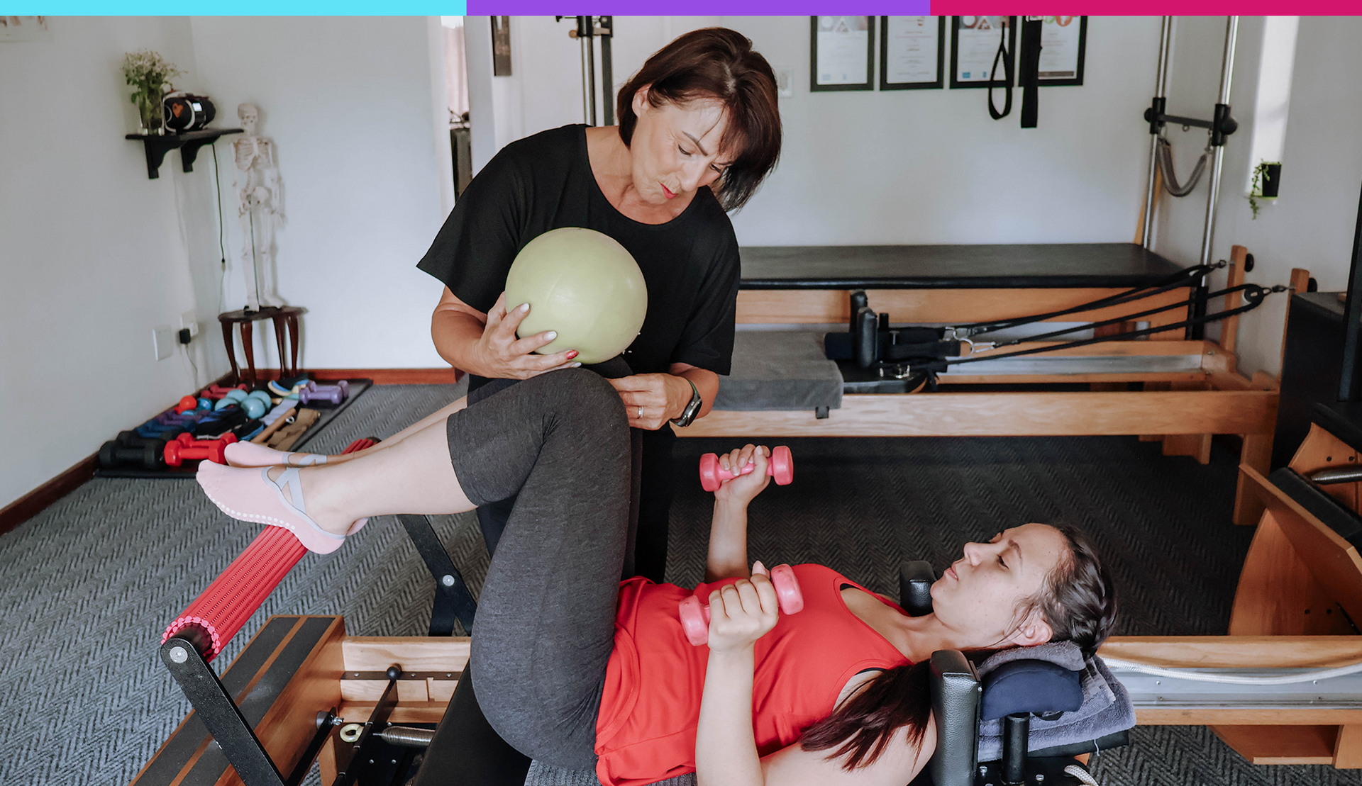 Instructor guiding a client through a Pilates exercise on a reformer bed in a studio