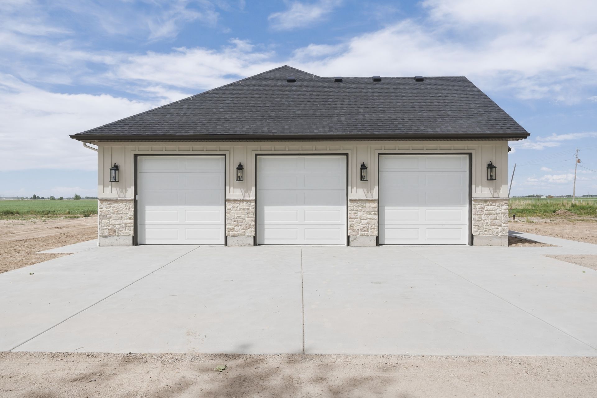 Three-car garage with gray roof and concrete driveway in a new suburban area