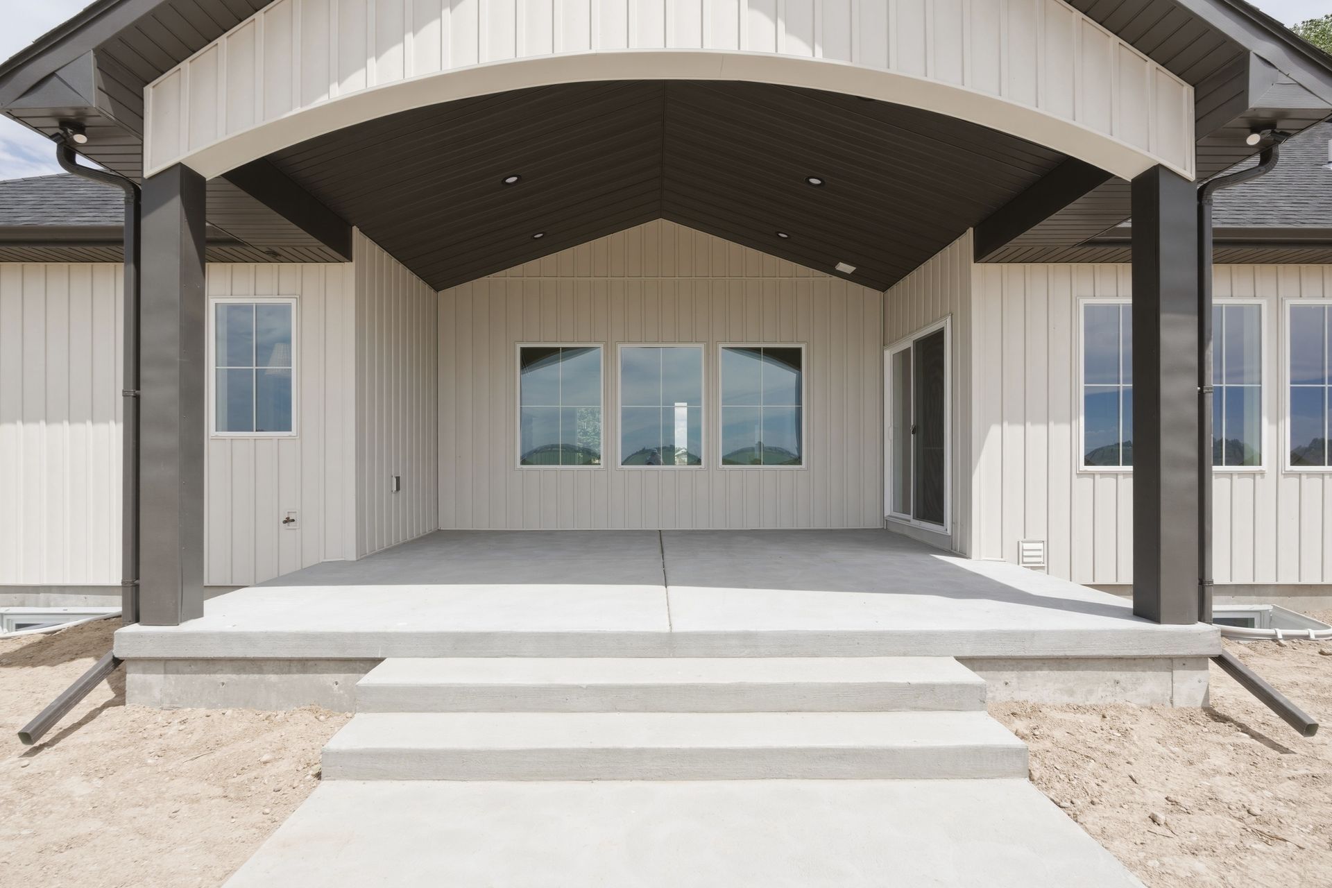 Front porch of a modern house with steps, white siding, and a covered entryway.