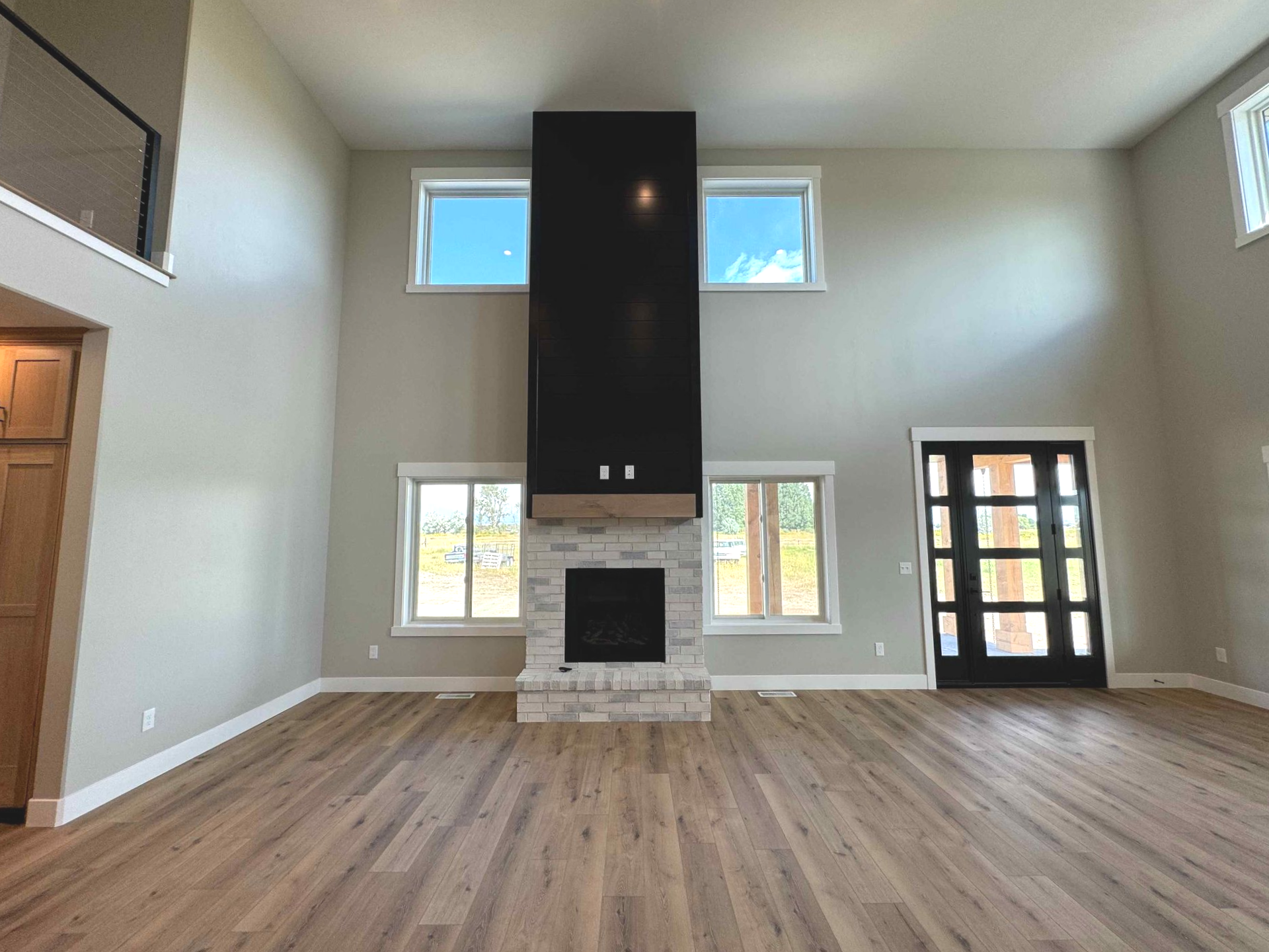 Spacious living room with leather sofas, brick accent wall, and a loft.
