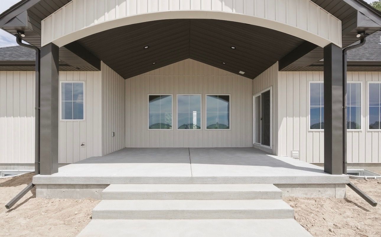 Front entrance of a modern house with covered porch, steps, and large windows