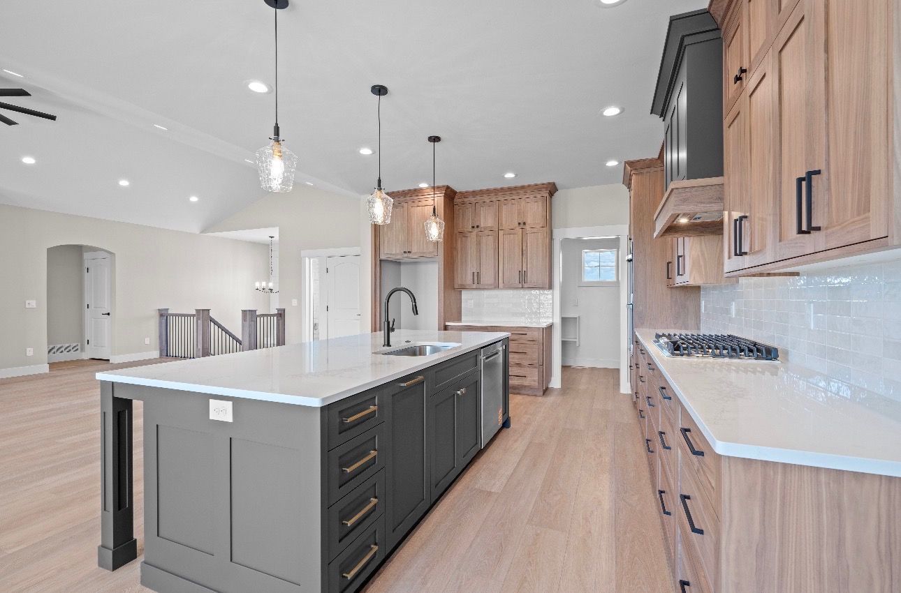 Modern kitchen with large island, wood cabinets, white counters, and stainless-steel appliances