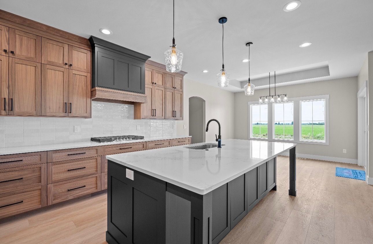 Modern kitchen with dark wood cabinets, large white island, and bright windows overlooking a patio