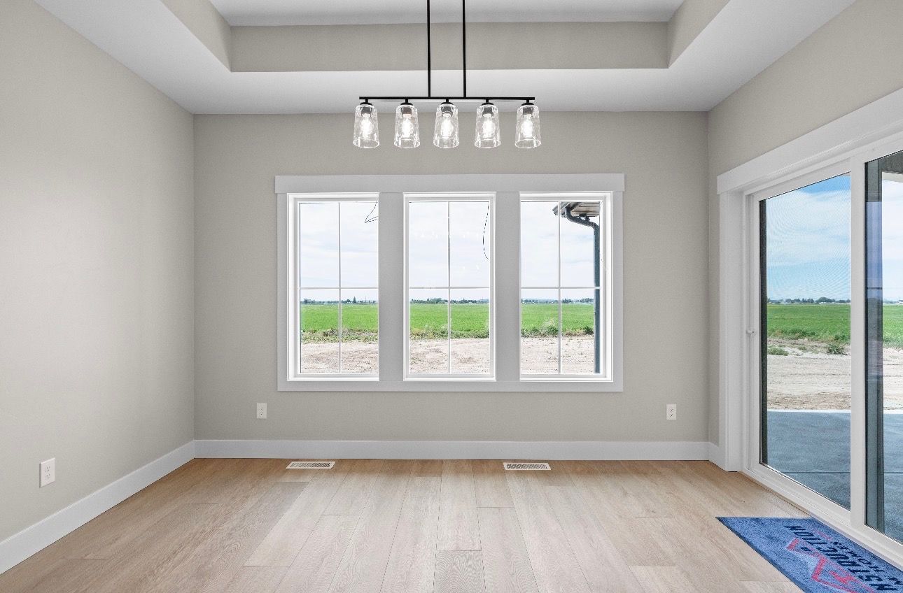 Empty modern room with light wood floor, large windows, and a glass door to the outside