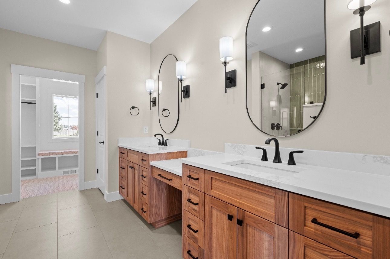Bright bathroom with double wood vanity, large mirrors, and white tiled floor.