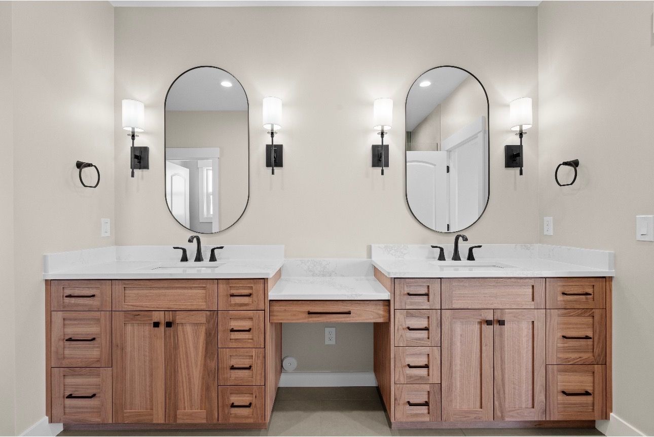 Double vanity bathroom with wood cabinets, white countertops, round mirrors, and wall sconces