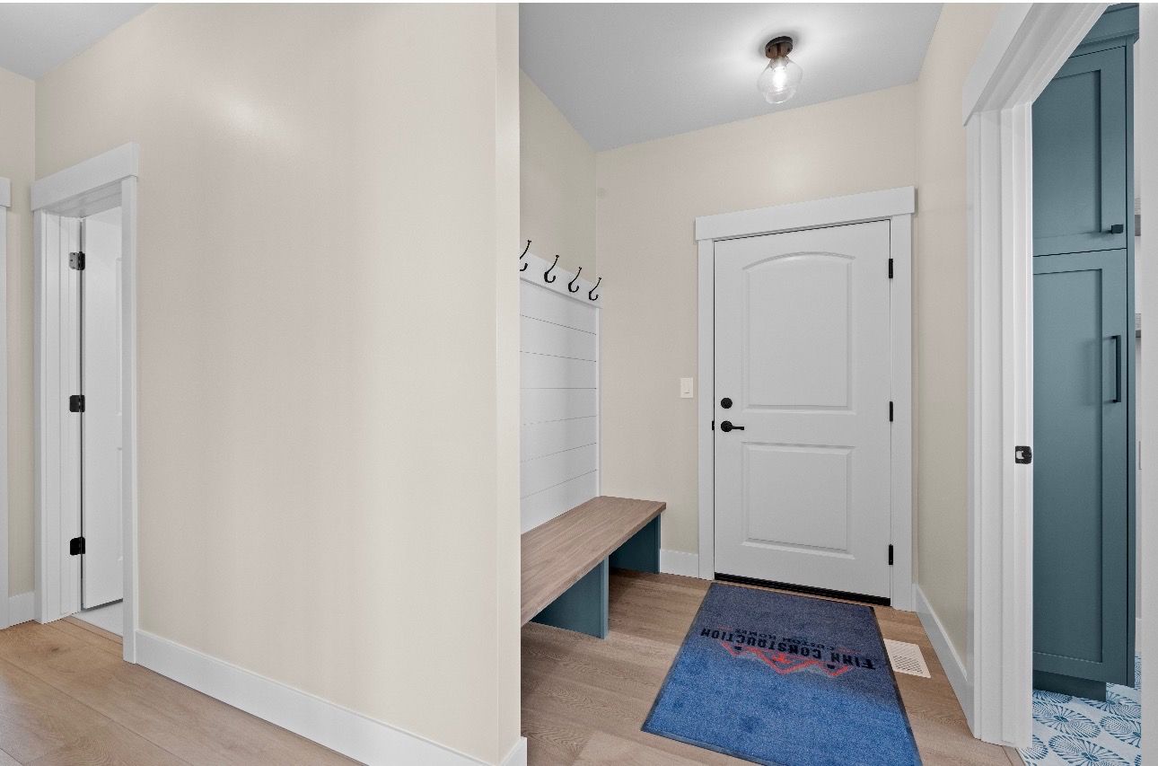 Hallway entry with white doors, bench, coat hooks, and colorful rugs on hardwood floor