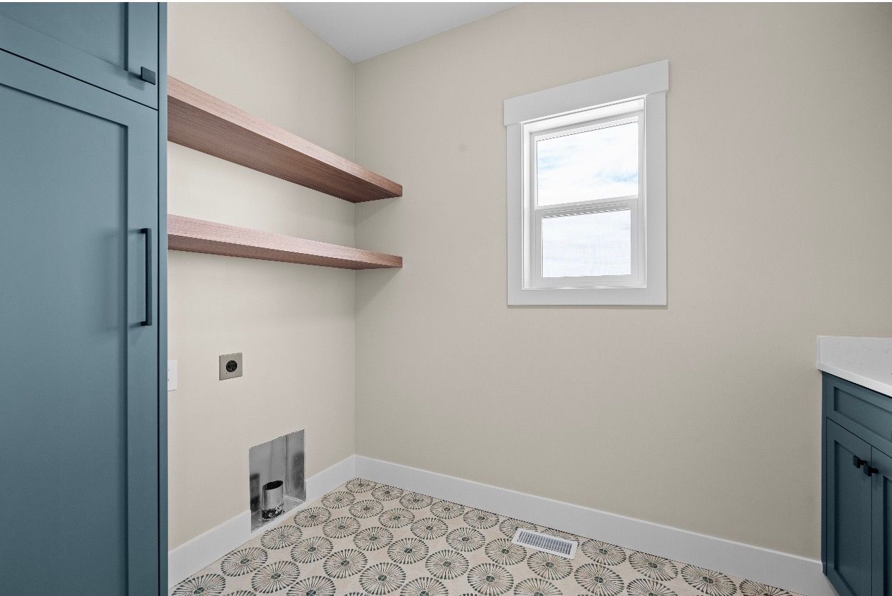 Small laundry room with blue cabinets, wood shelves, and a window.