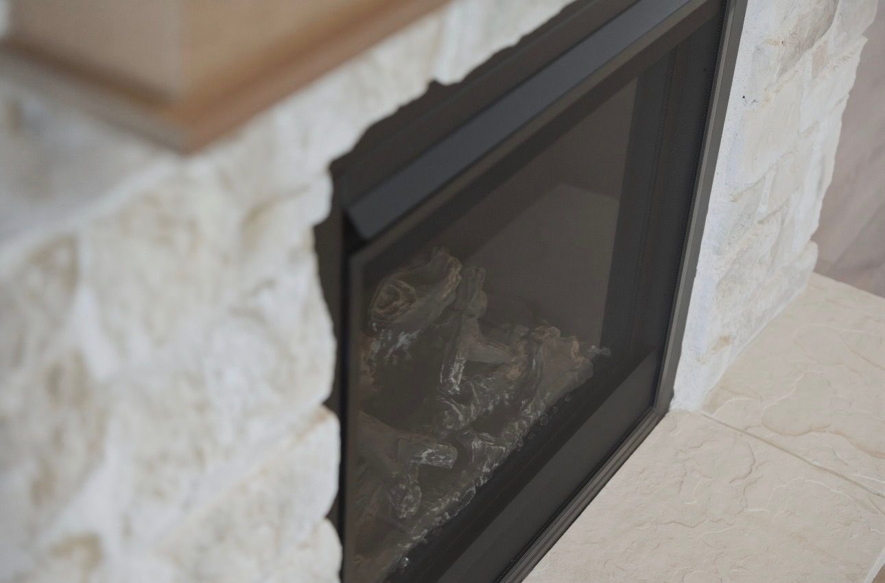 Black-framed glass fireplace set into a stone wall and hearth