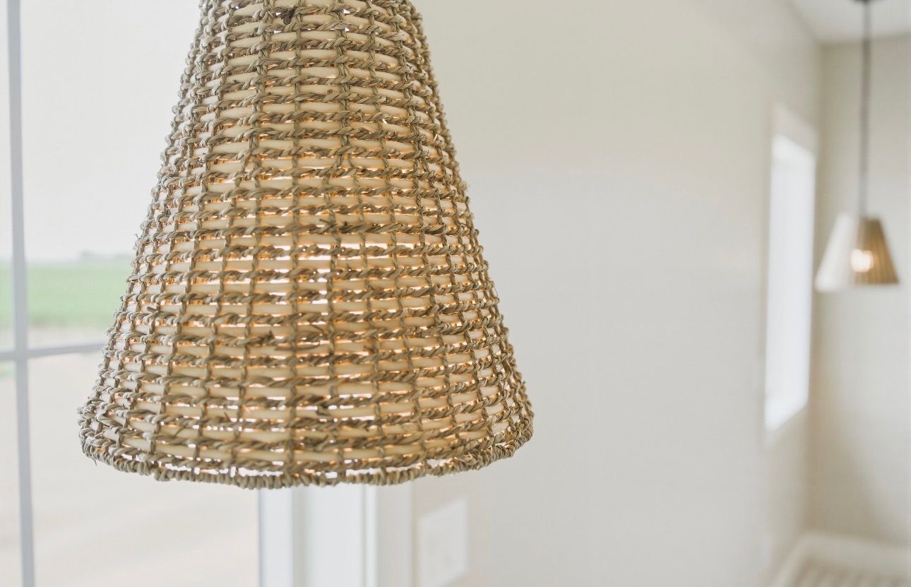 Woven beige pendant lamp hanging in a bright room with white walls