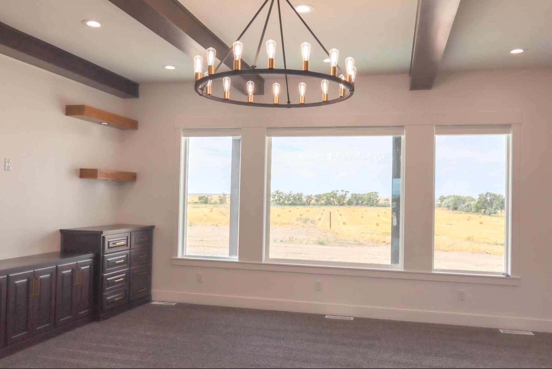 Bedroom with green accent wall, gray bed, light wood floors, two windows, and a ceiling fan.