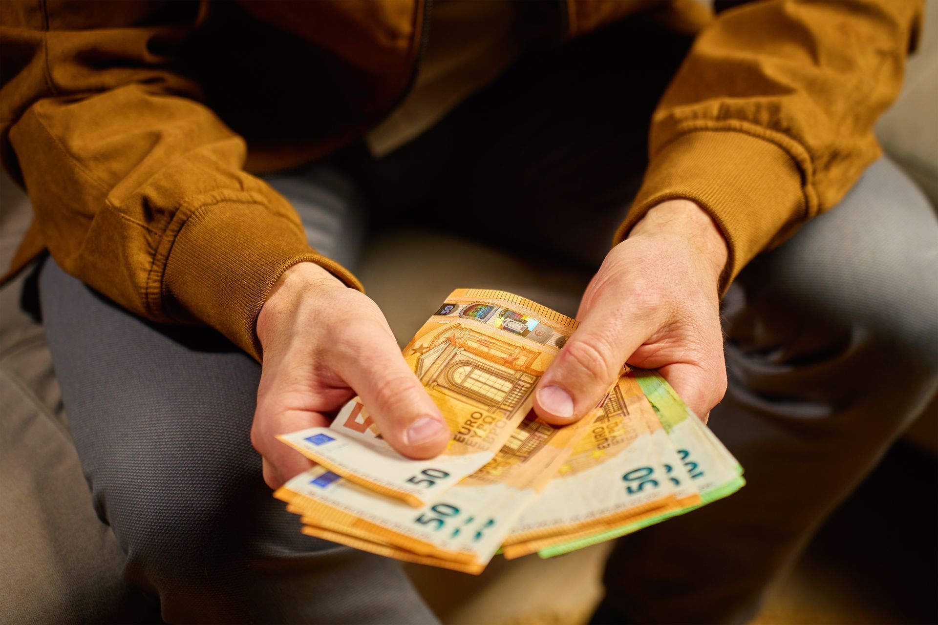 Person holding a stack of Euro banknotes.
