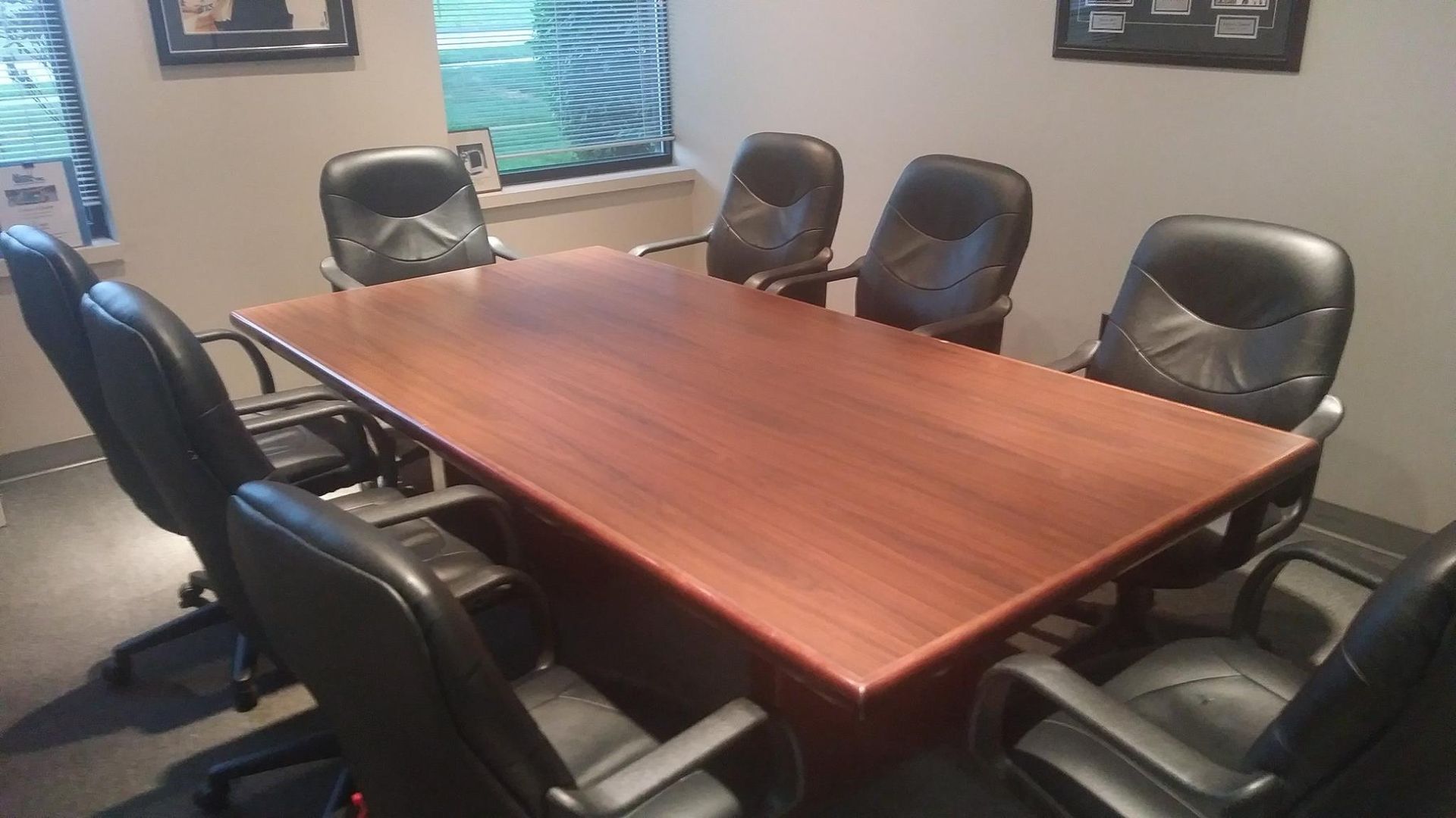 A conference room with a wooden table and black chairs