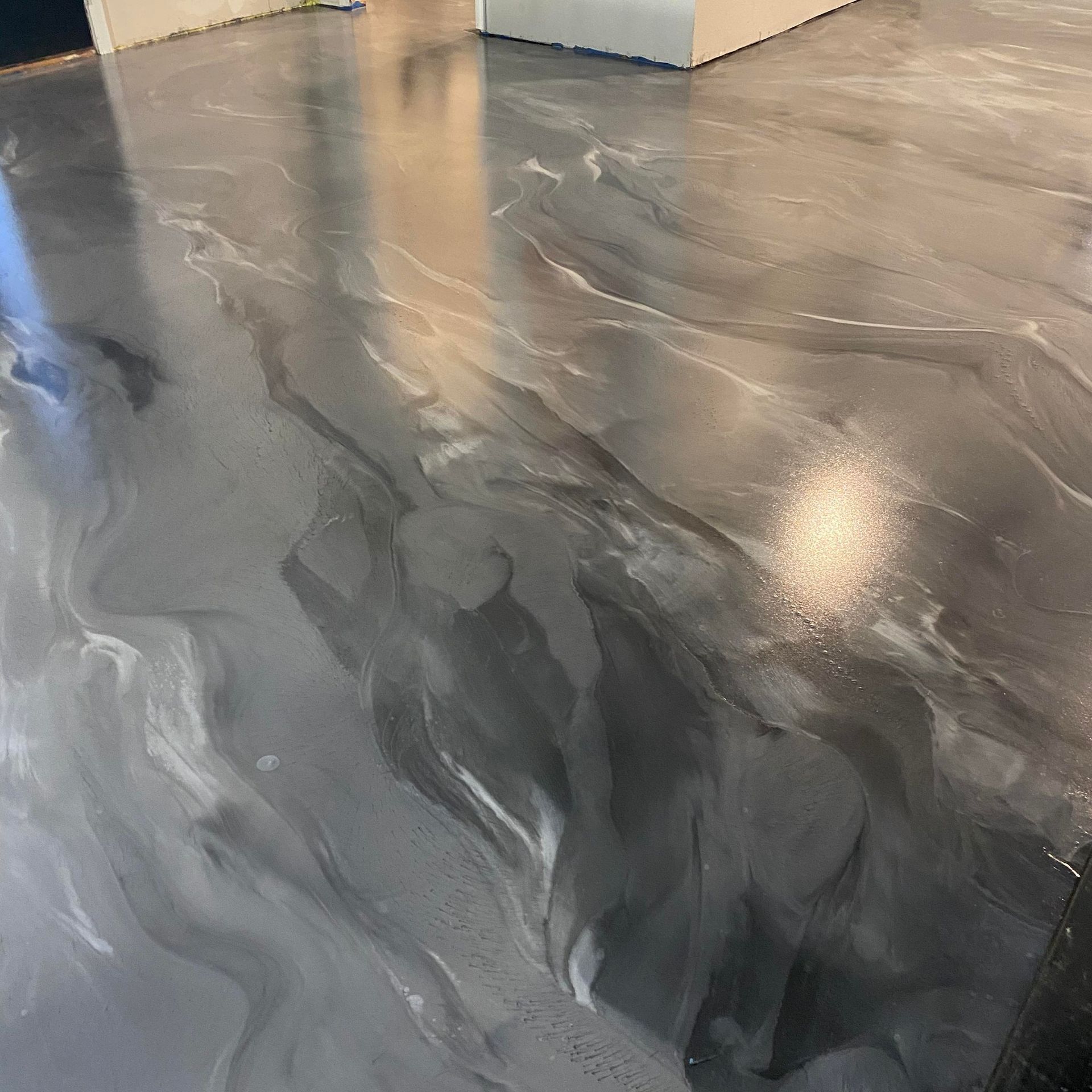 Gray and silver metallic epoxy flooring with swirling patterns and reflections.