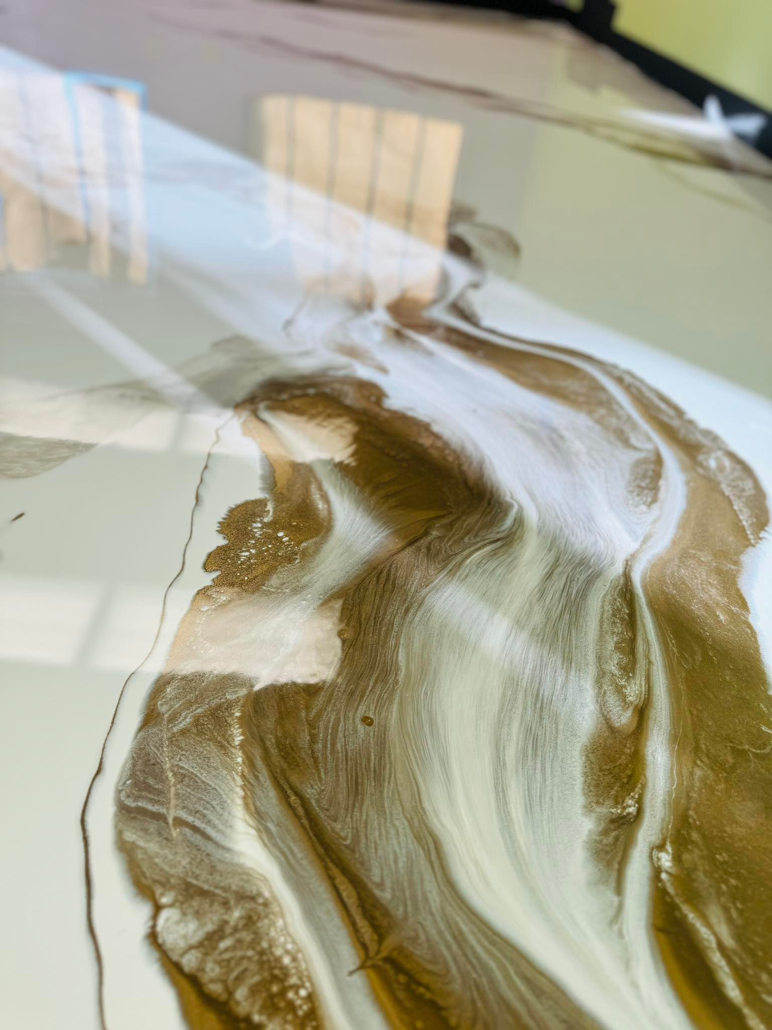 White and gold marbled resin art with dark veins; reflective surface.