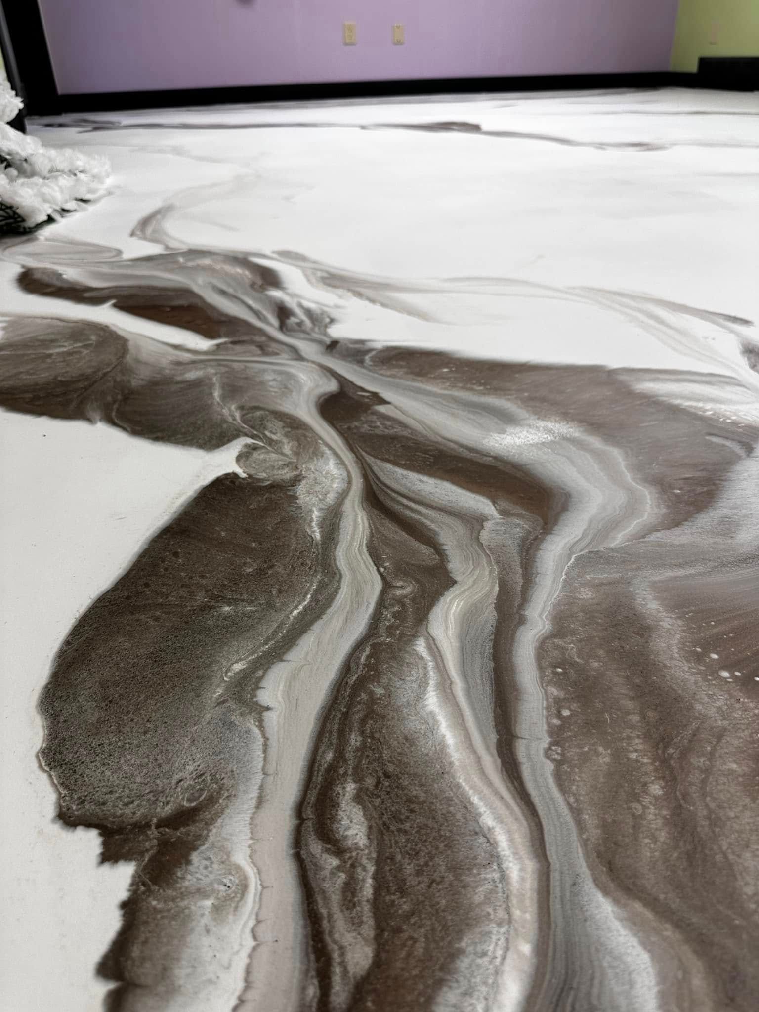 Foam on floor, flowing in swirls of white and brown. Purple wall in background.
