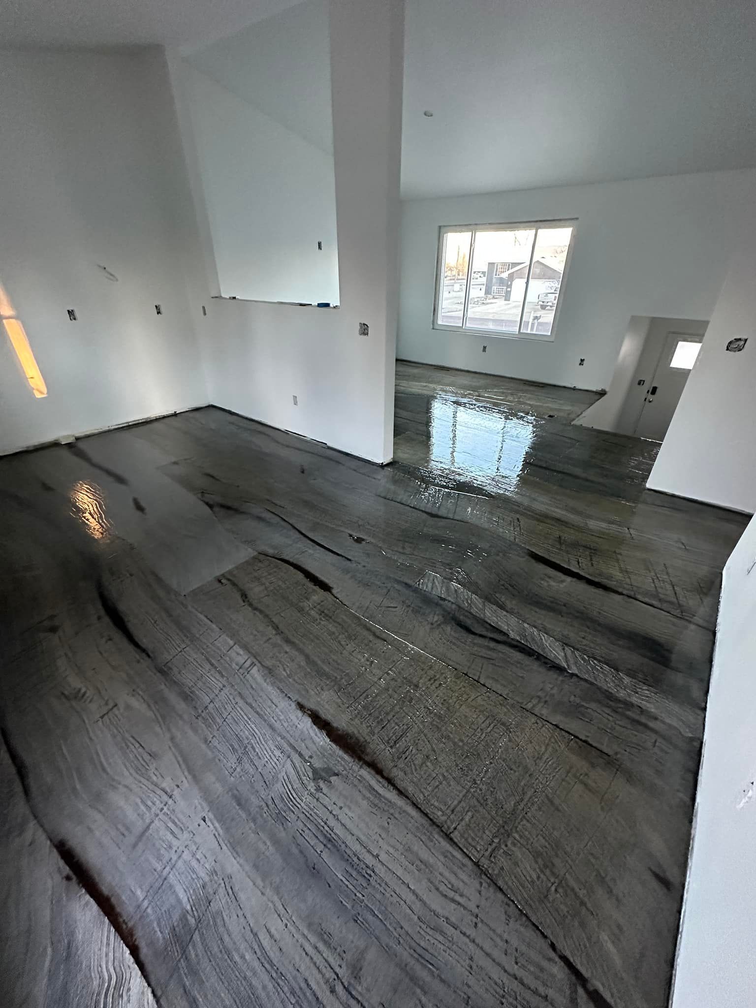 Gray-toned, wood-look concrete flooring in a bright, white-walled room with a window.