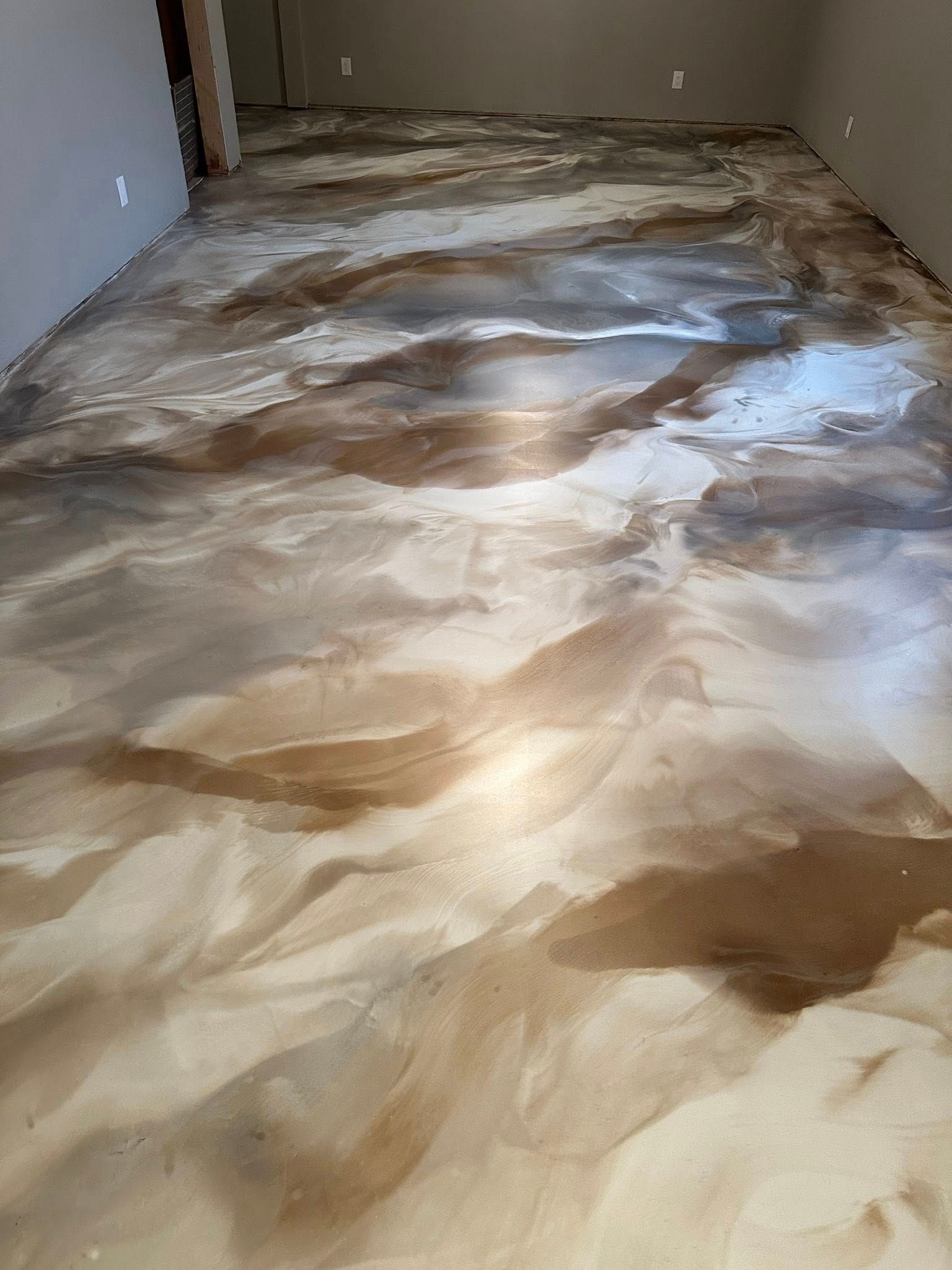 Metallic epoxy floor in shades of brown, bronze, and silver with a flowing, marbled appearance.