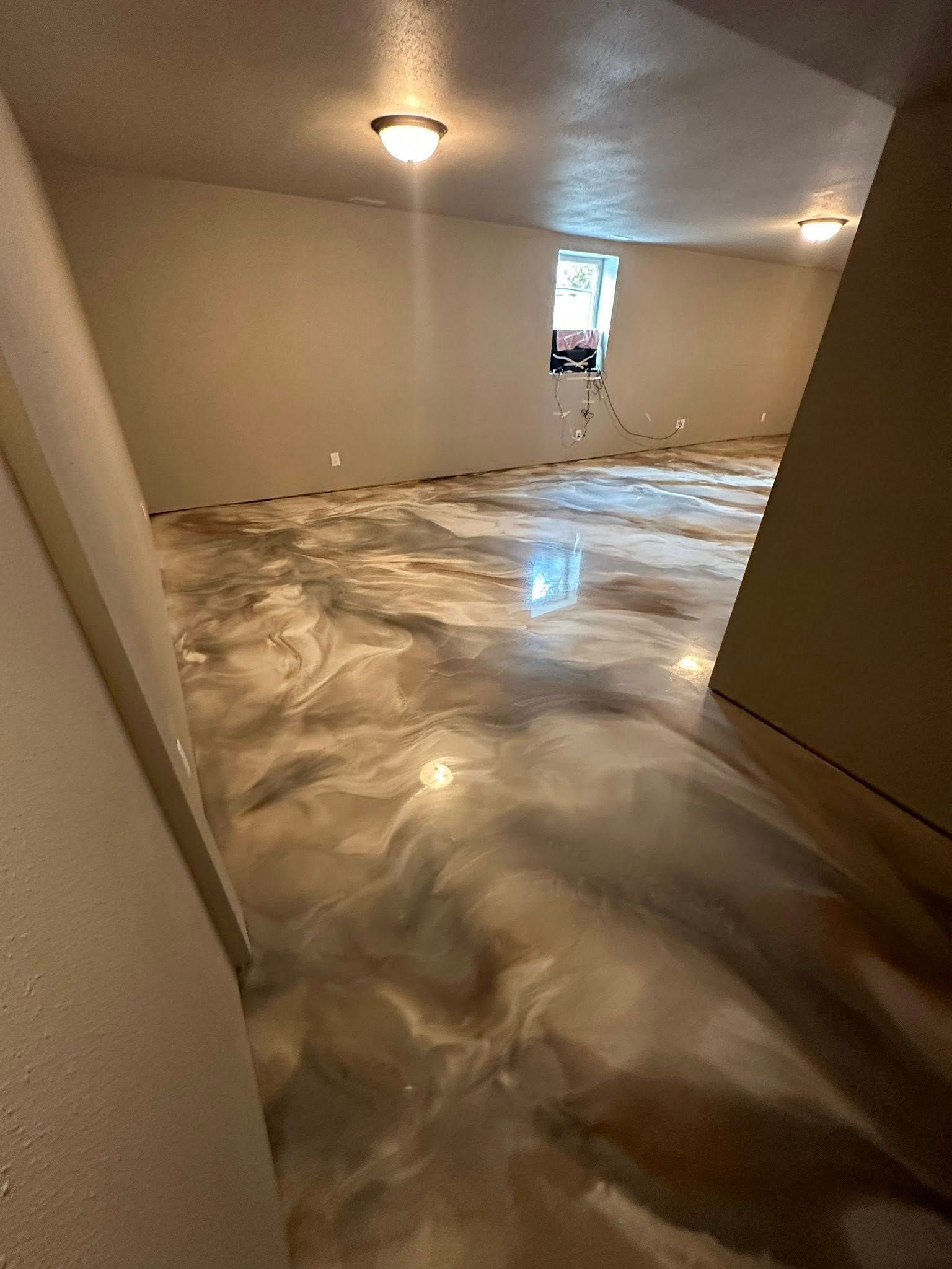 Room with metallic epoxy flooring, tan walls, and two ceiling lights.