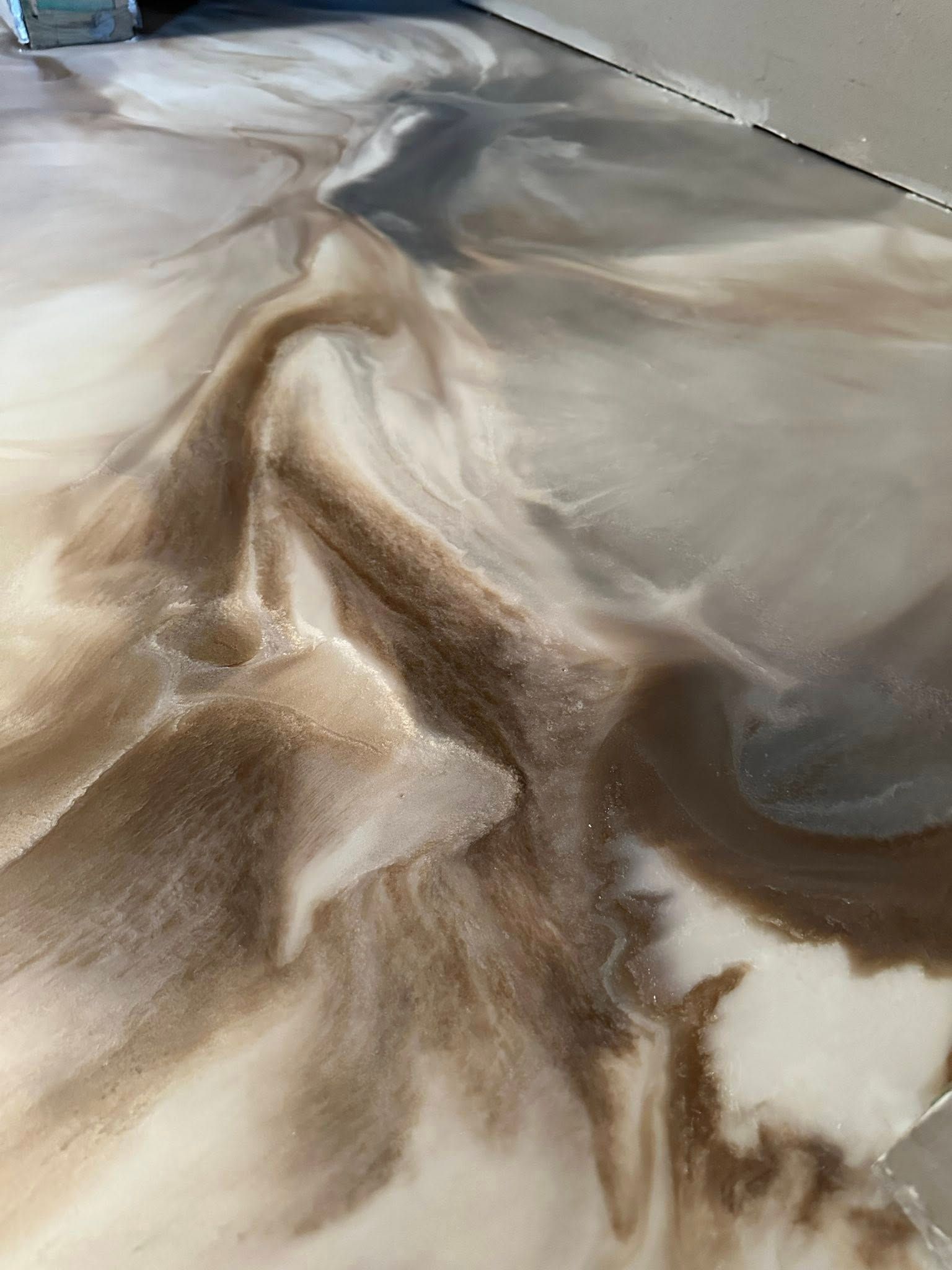 Swirling brown, tan, and white epoxy floor with a glossy finish.