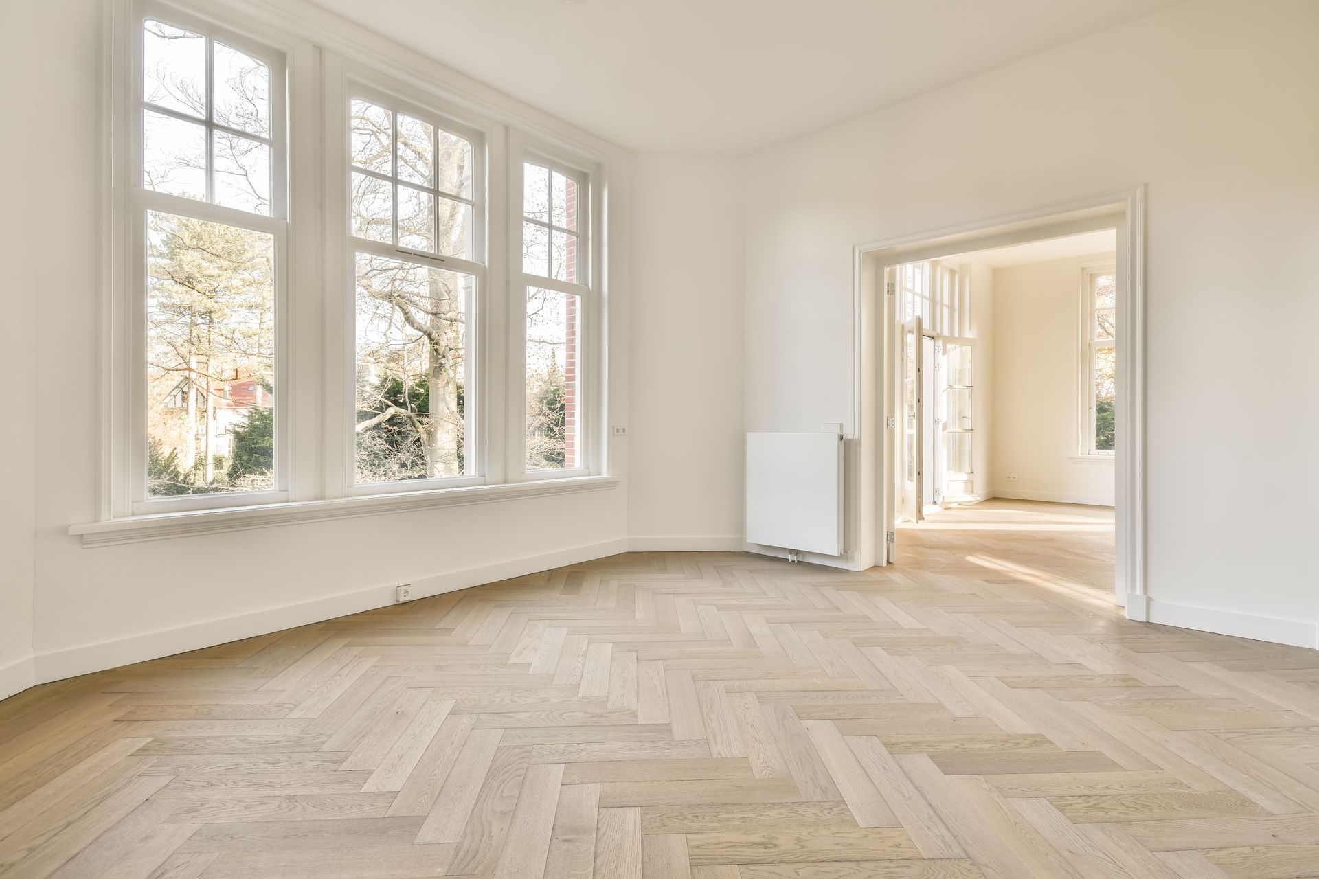 An empty room with a wooden floor and lots of windows