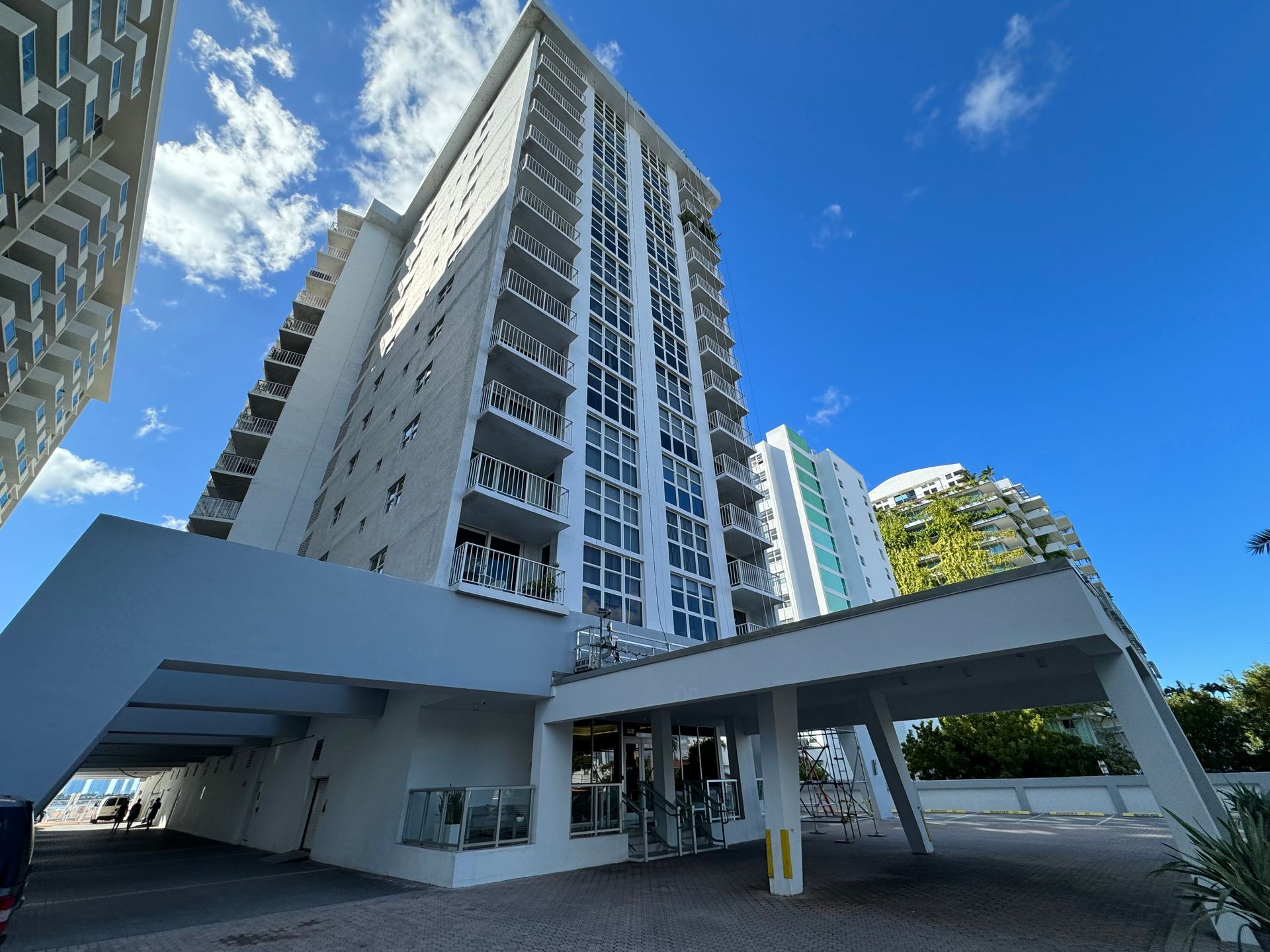 Tall white apartment building with balconies, under a blue sky.