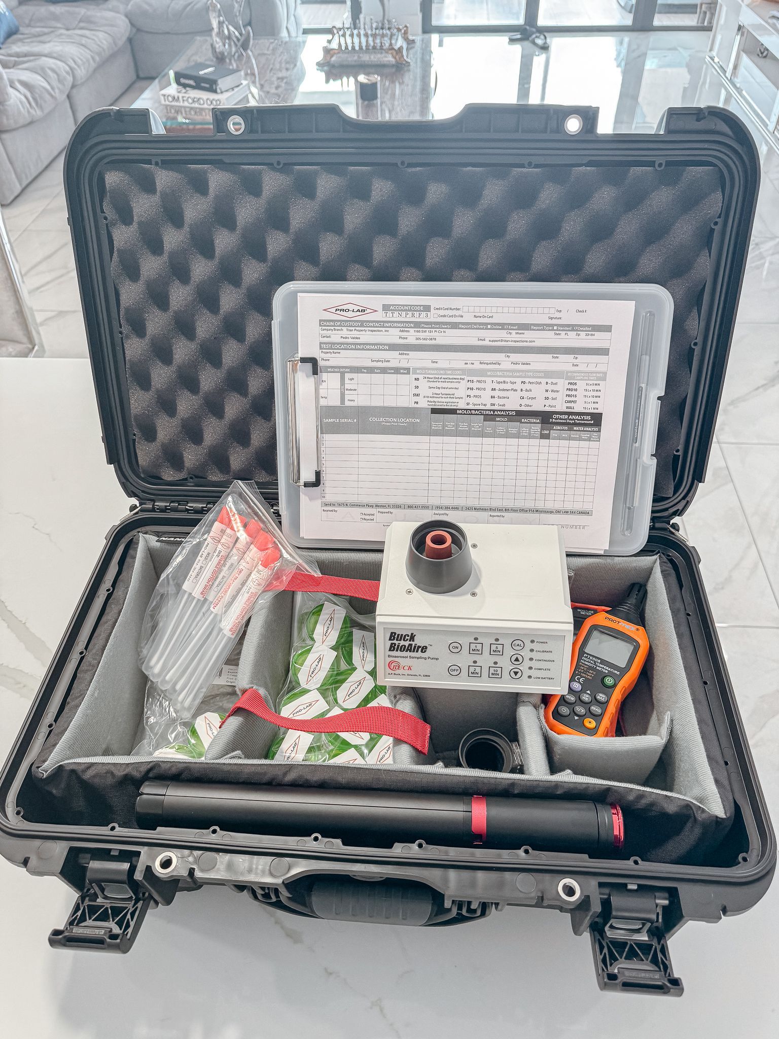 Open black case with foam, equipment, papers. Gray inserts hold items like a meter and other tools.