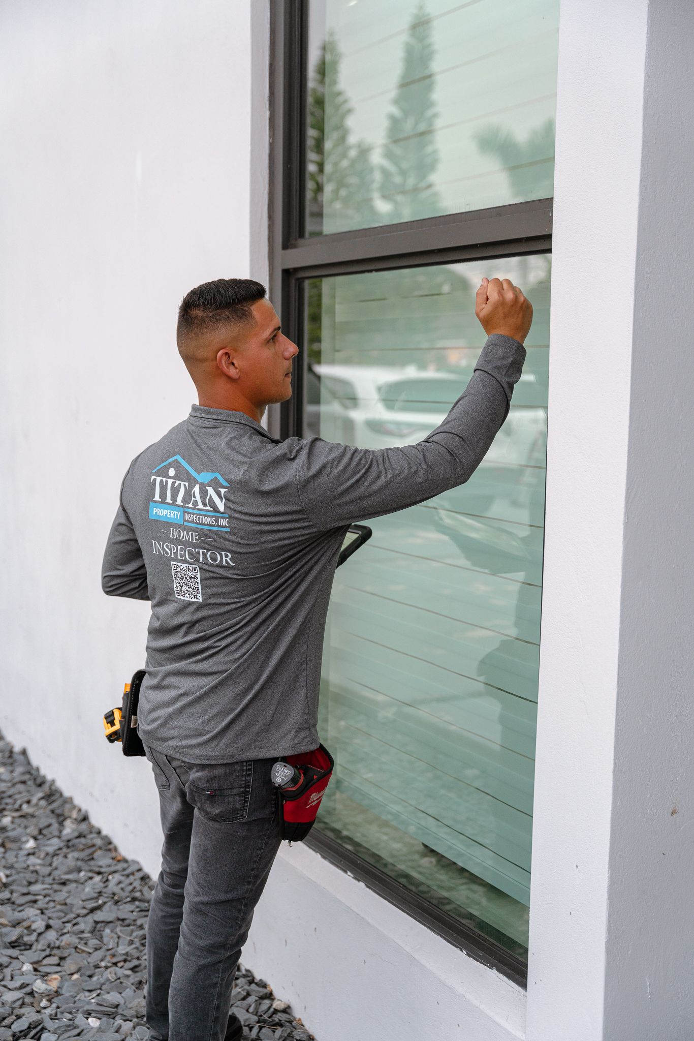 Man in gray shirt installing window tint on a building.