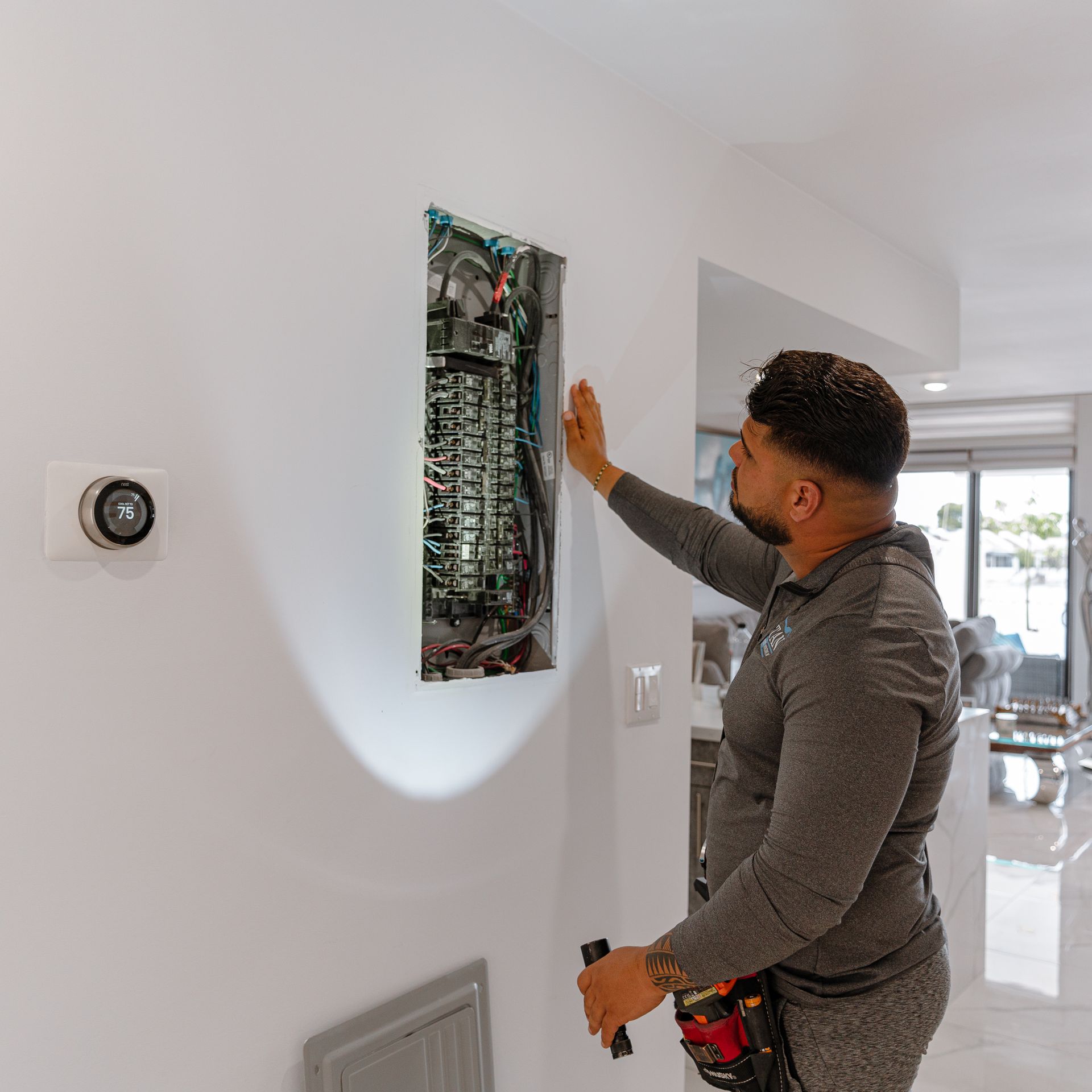 Electrician examining an electrical panel on a white wall in a modern home.