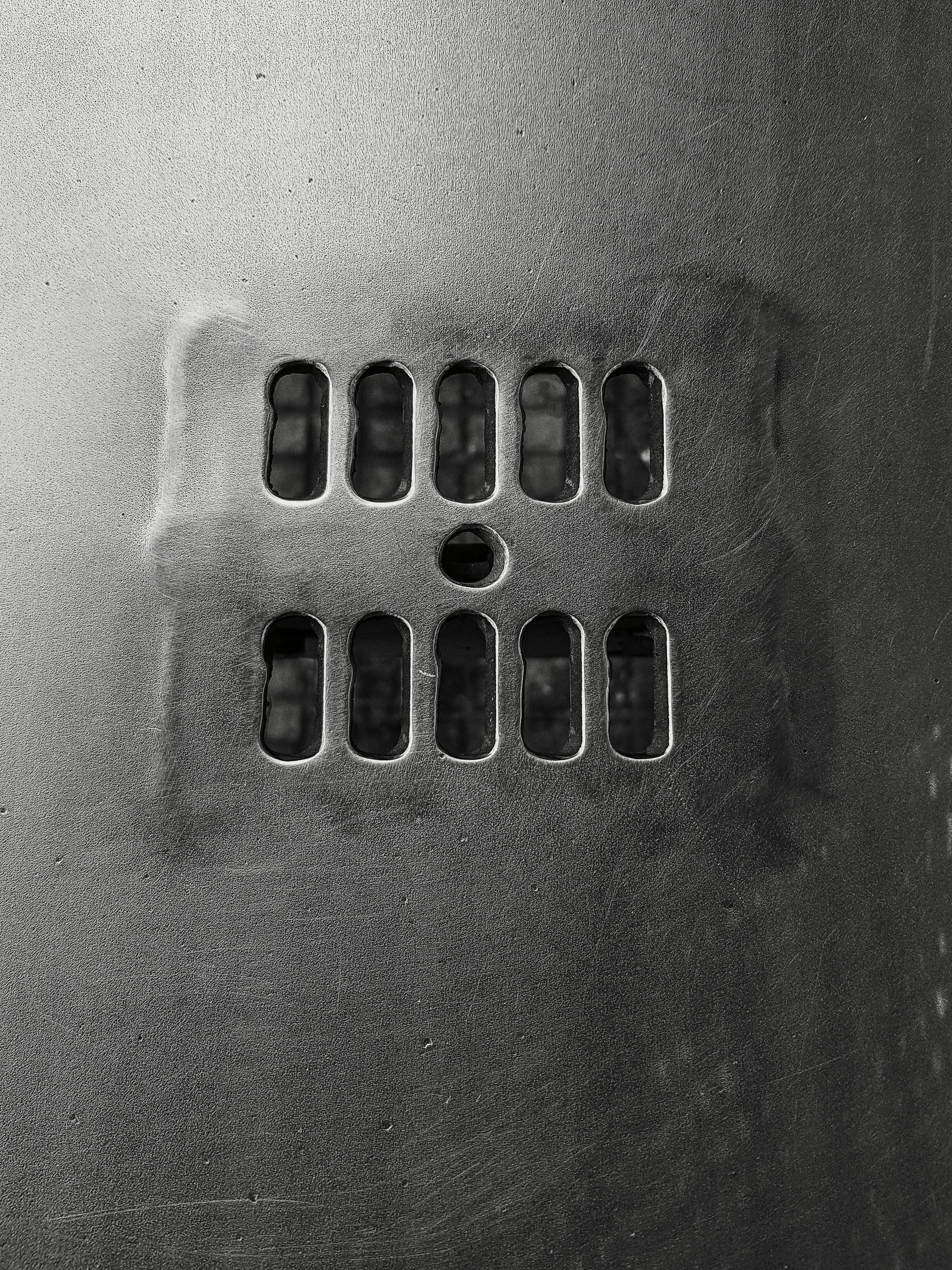 Metal panel with two rows of rectangular vents and a central circular vent.