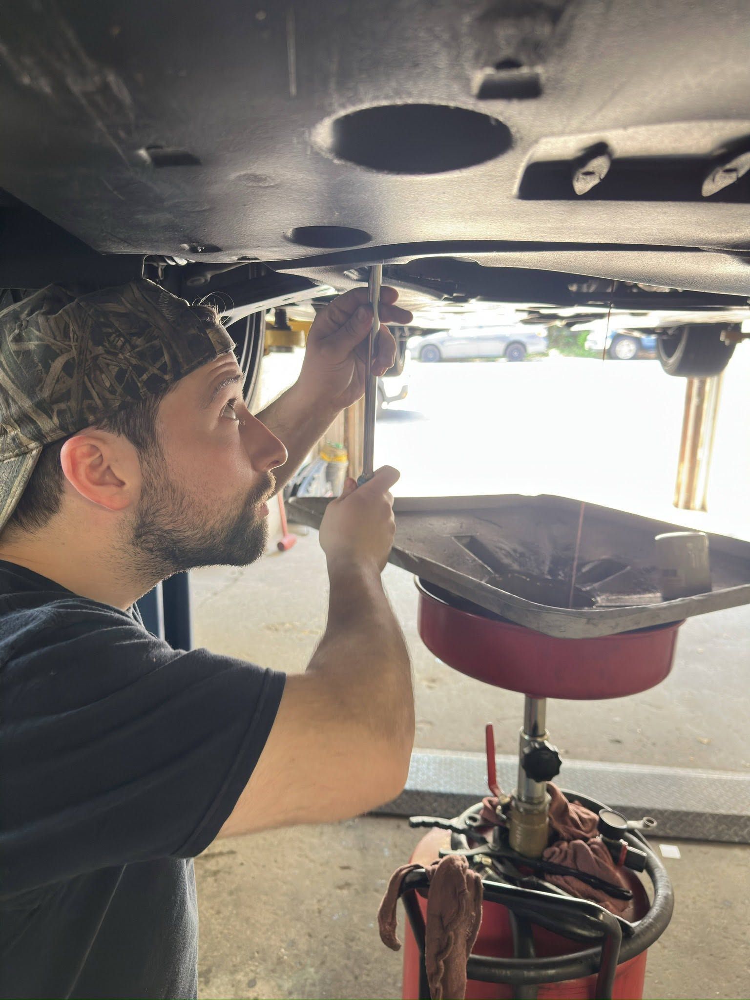 Mechanic tightening bolts under a car on a lift in a garage | Braddock Motors Service