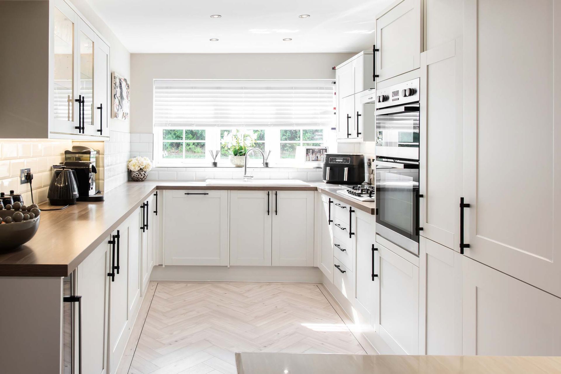 A kitchen with white cabinets , wooden counter tops , and stainless steel appliances.