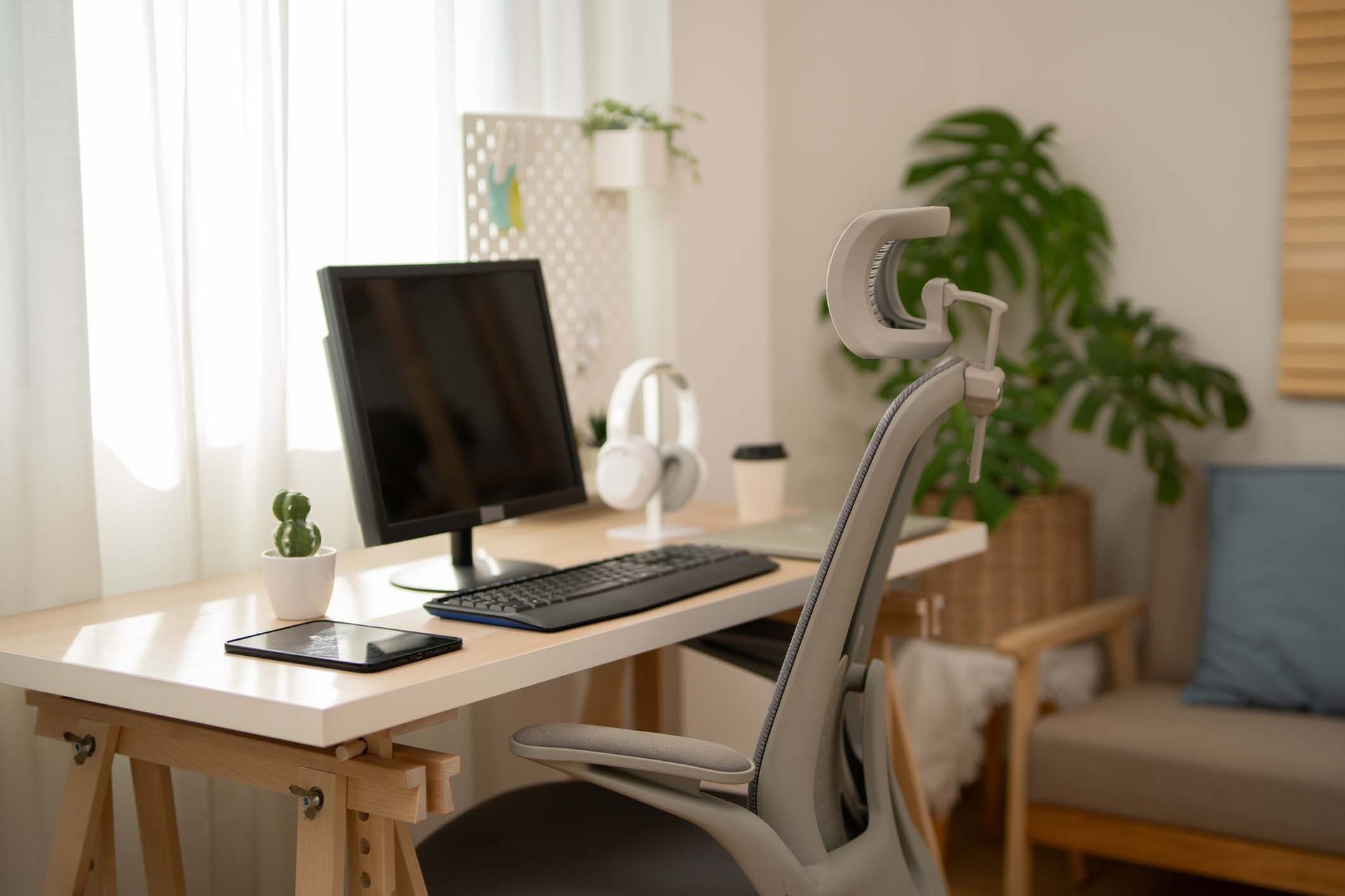 A desk with a computer and headphones on it in a living room.