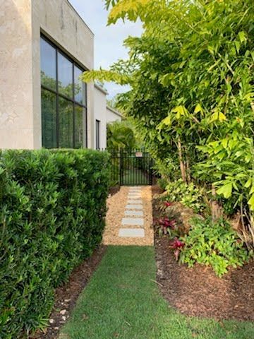 Stone path through a lush green garden with a building on the left.