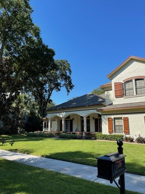 Two-story house with green lawn, sidewalk, and black mailbox on a sunny day.