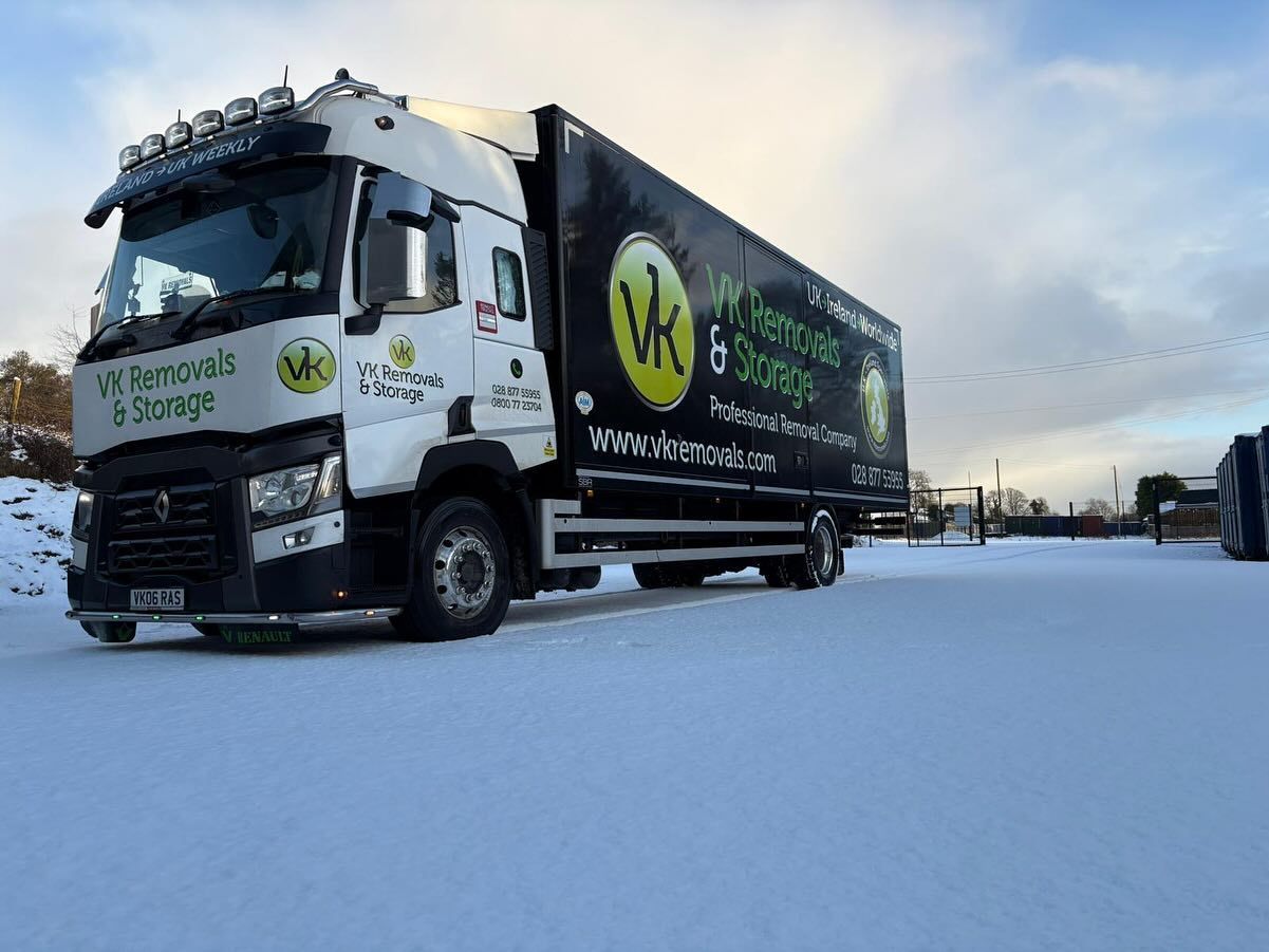 A white and black semi-truck with logos on the side and front parked on a snow-covered surface.
