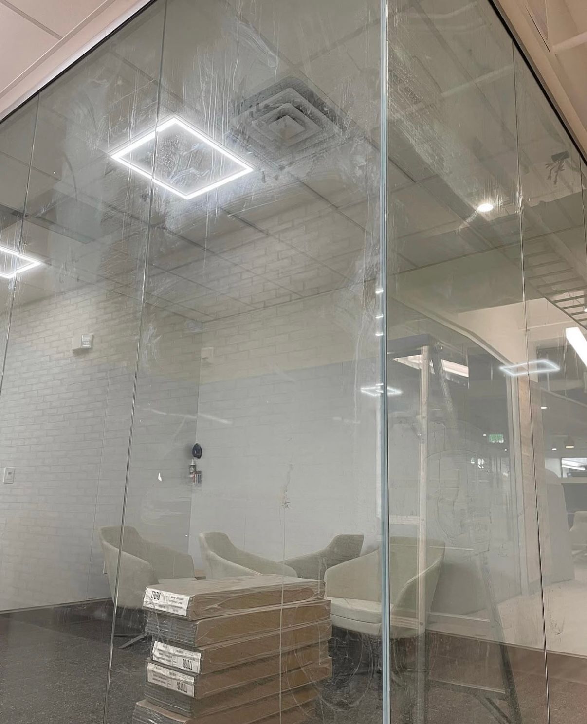 Glass wall of a room with chairs and square light fixture.