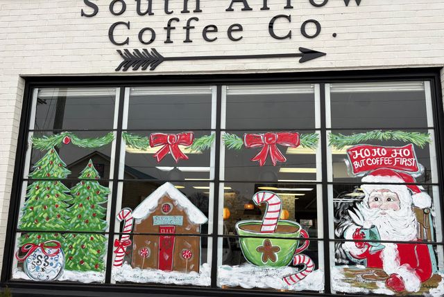 South Arrow Coffee Co. storefront window with hand-painted festive holiday scenes, including trees, Santa, and a mug.