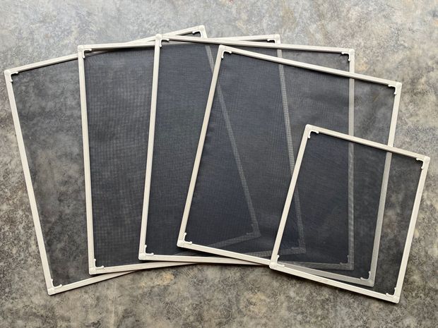 Five rectangular window screens with dark mesh and light-colored frames arranged in a fanned, overlapping pile.