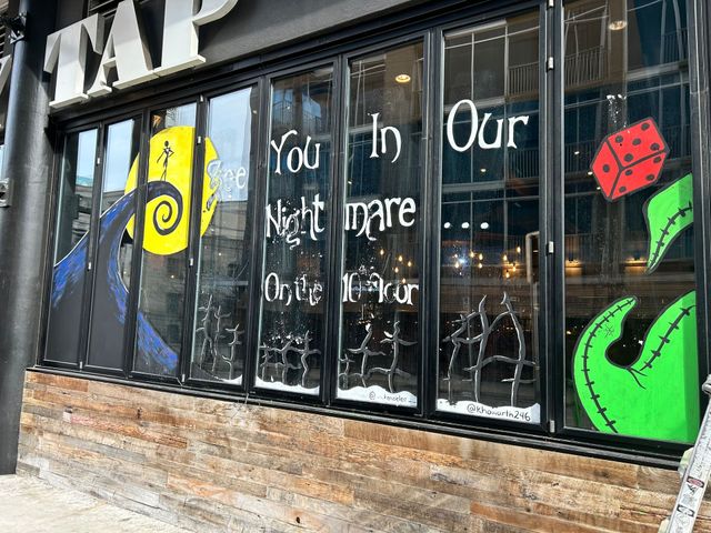 A storefront window painted with "The Nightmare Before Christmas" characters, including Jack Skellington and a red die.