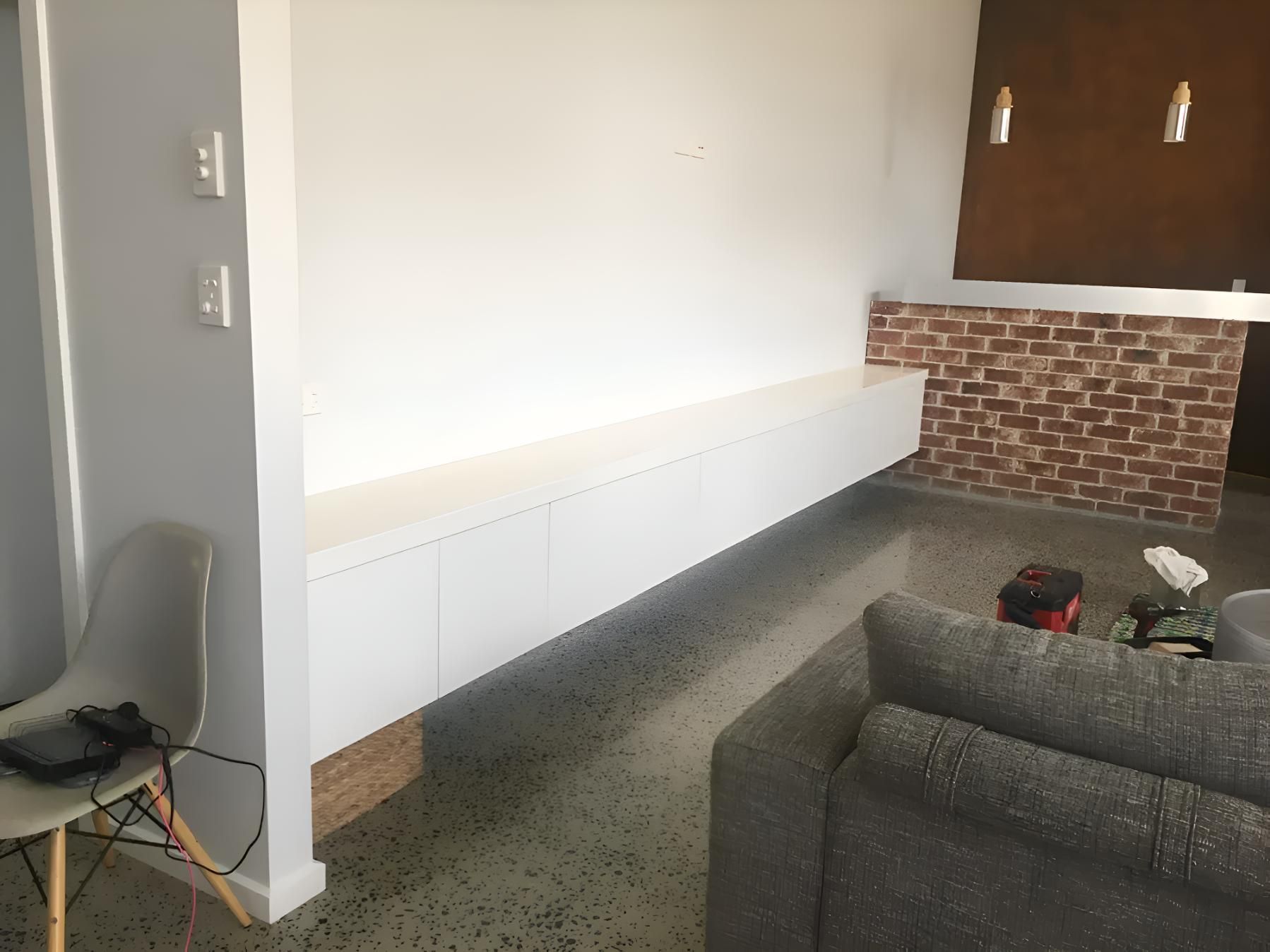 A Living Room With A Couch , Chair And A Long White Shelf — Hey Presto Kitchens & Renovations in Armidale, NSW