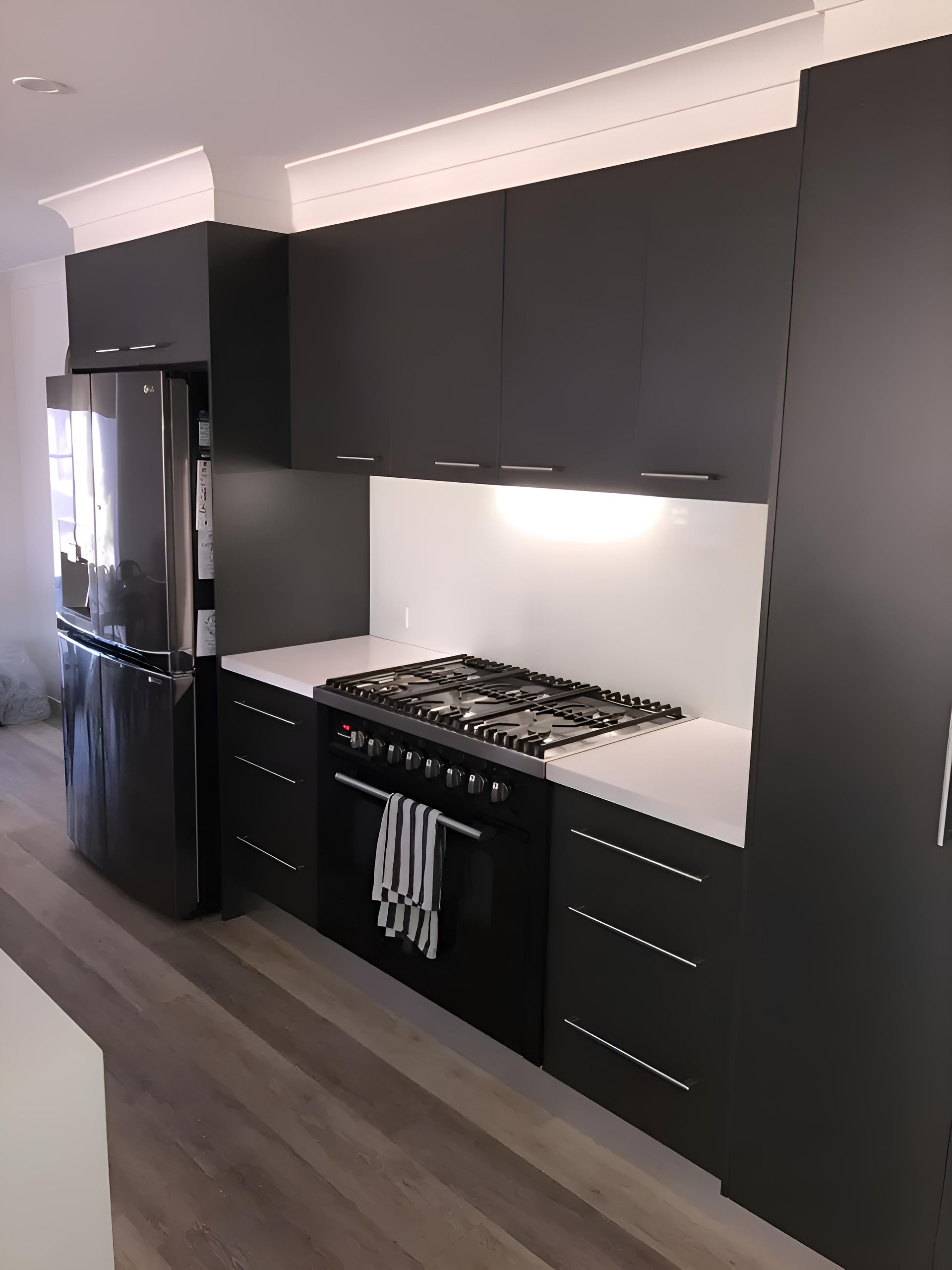 A Kitchen With Black Cabinets and a Stove Top Oven — Hey Presto Kitchens & Renovations in Armidale, NSW